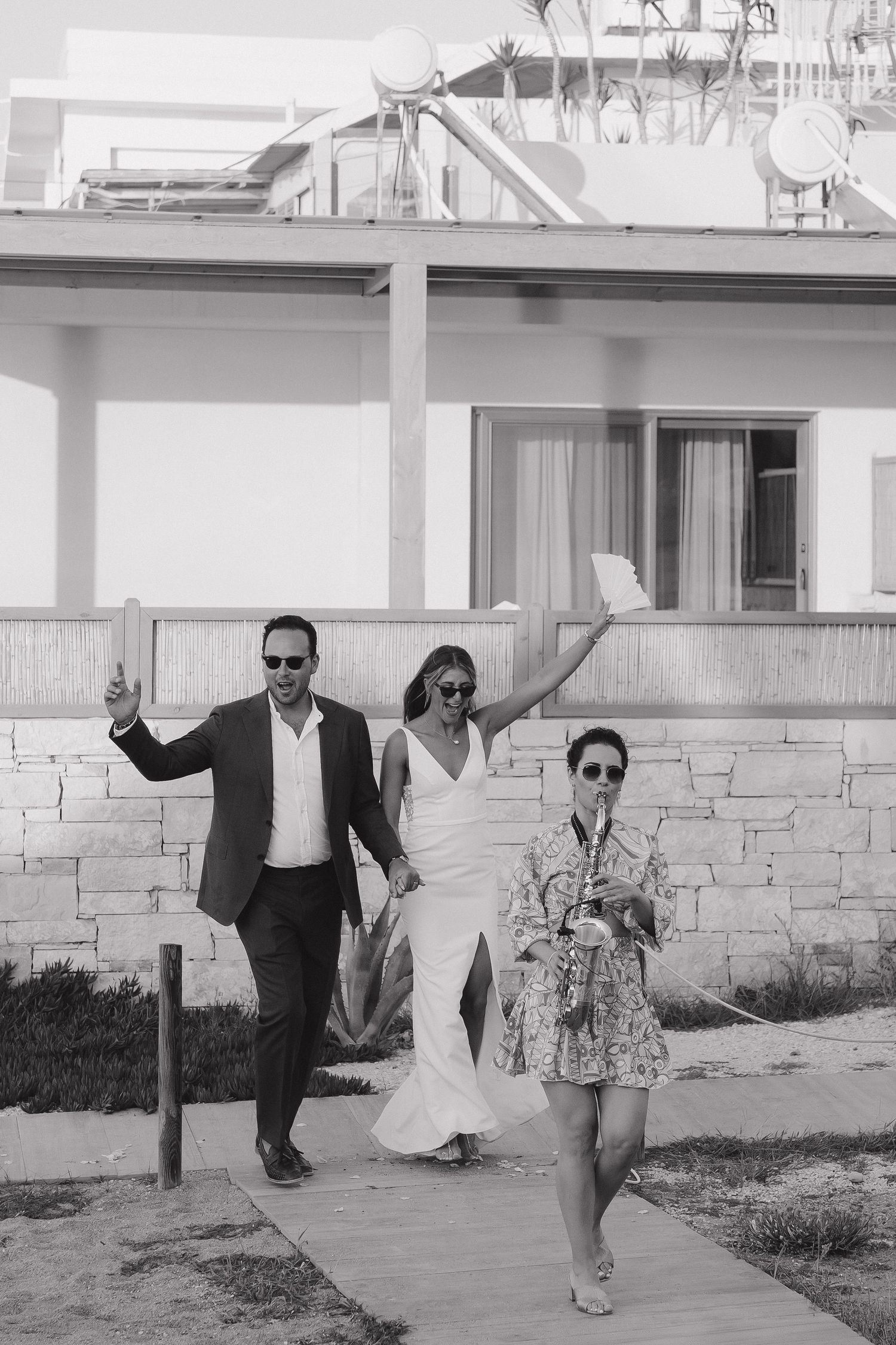Wedding party walking along seaside path in black and white photography.