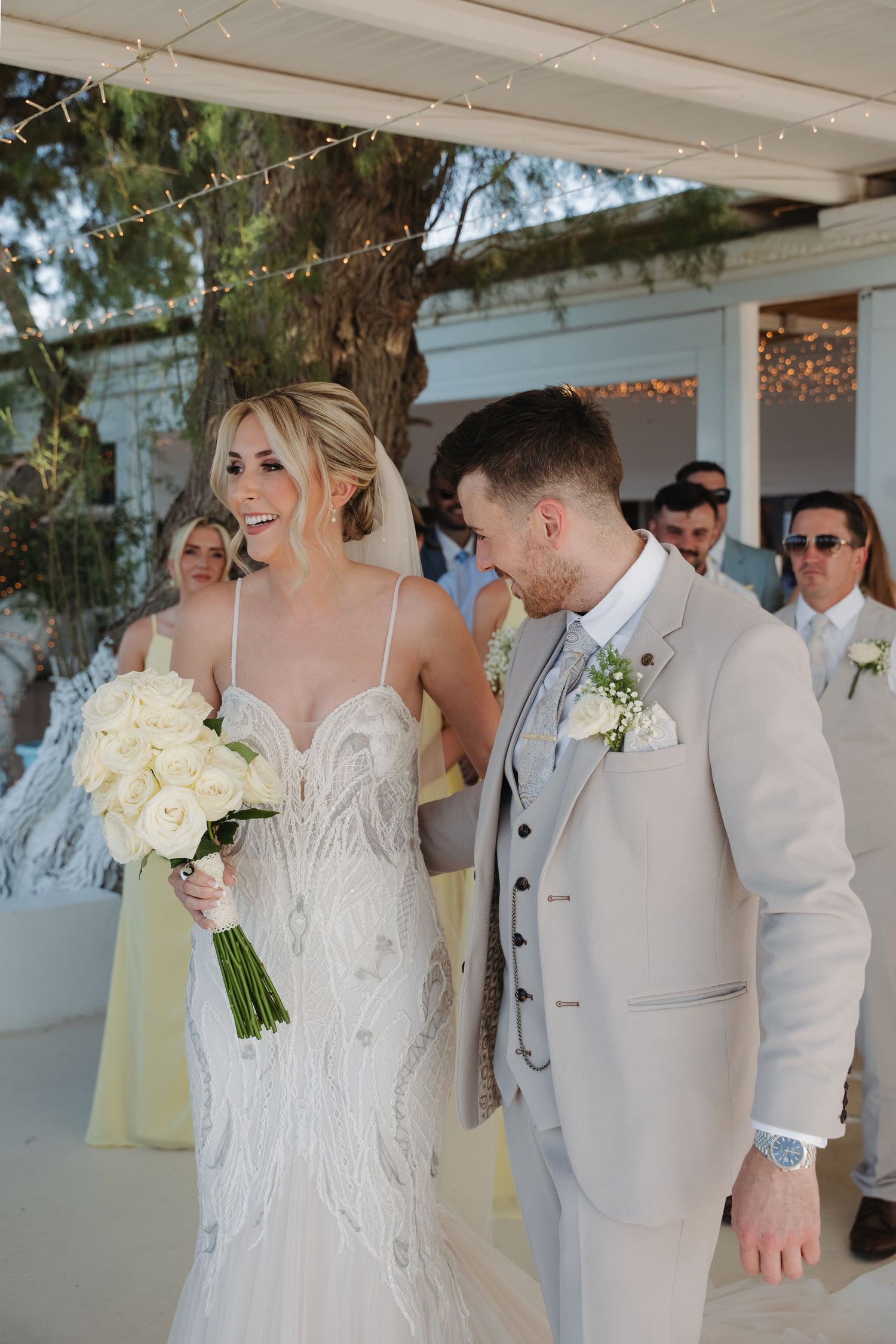 A joyful wedding couple shares a laugh during their beachside ceremony.