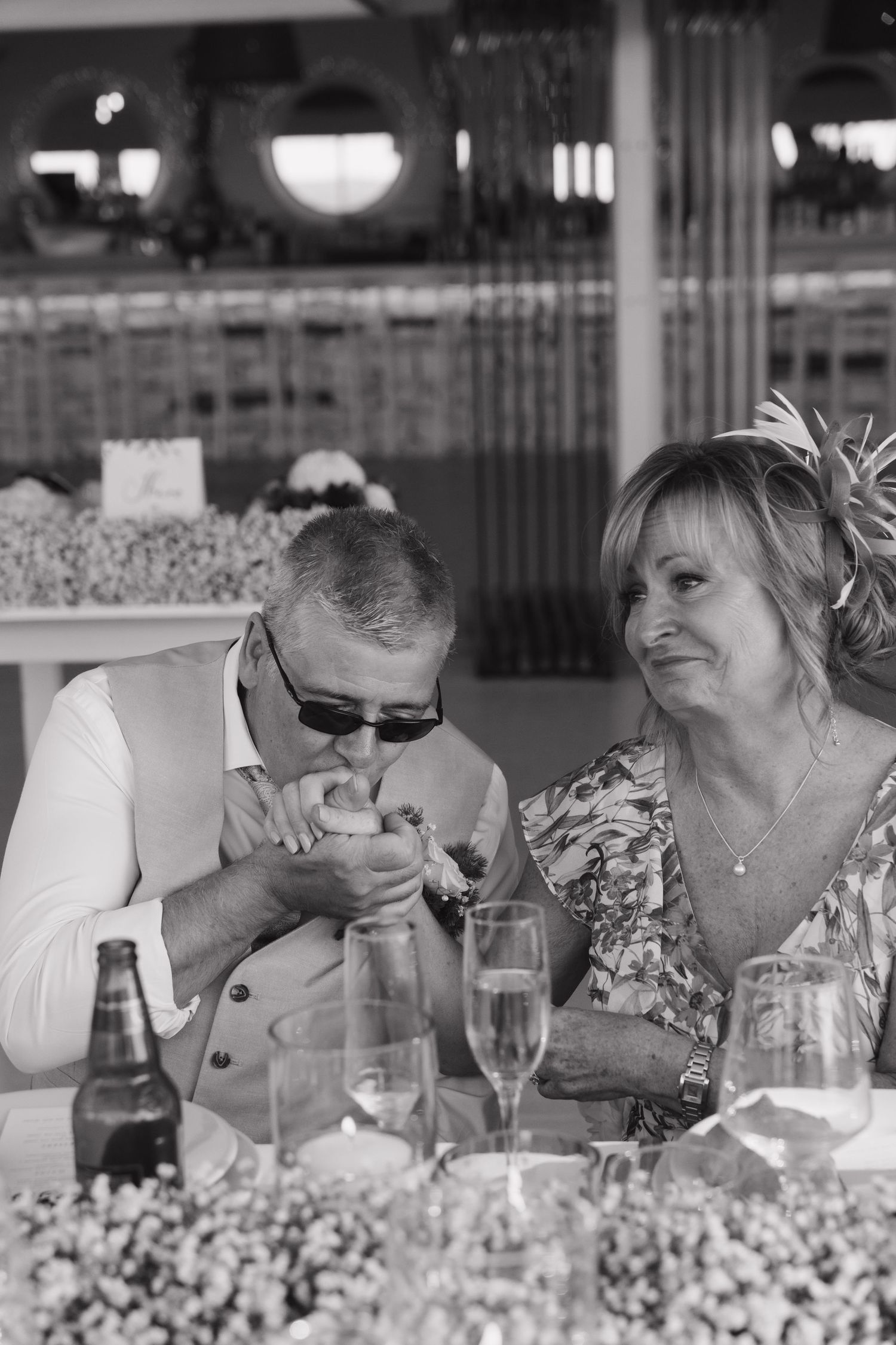 Candid black and white photo of guests dining at table decorated with baby's breath flowers.