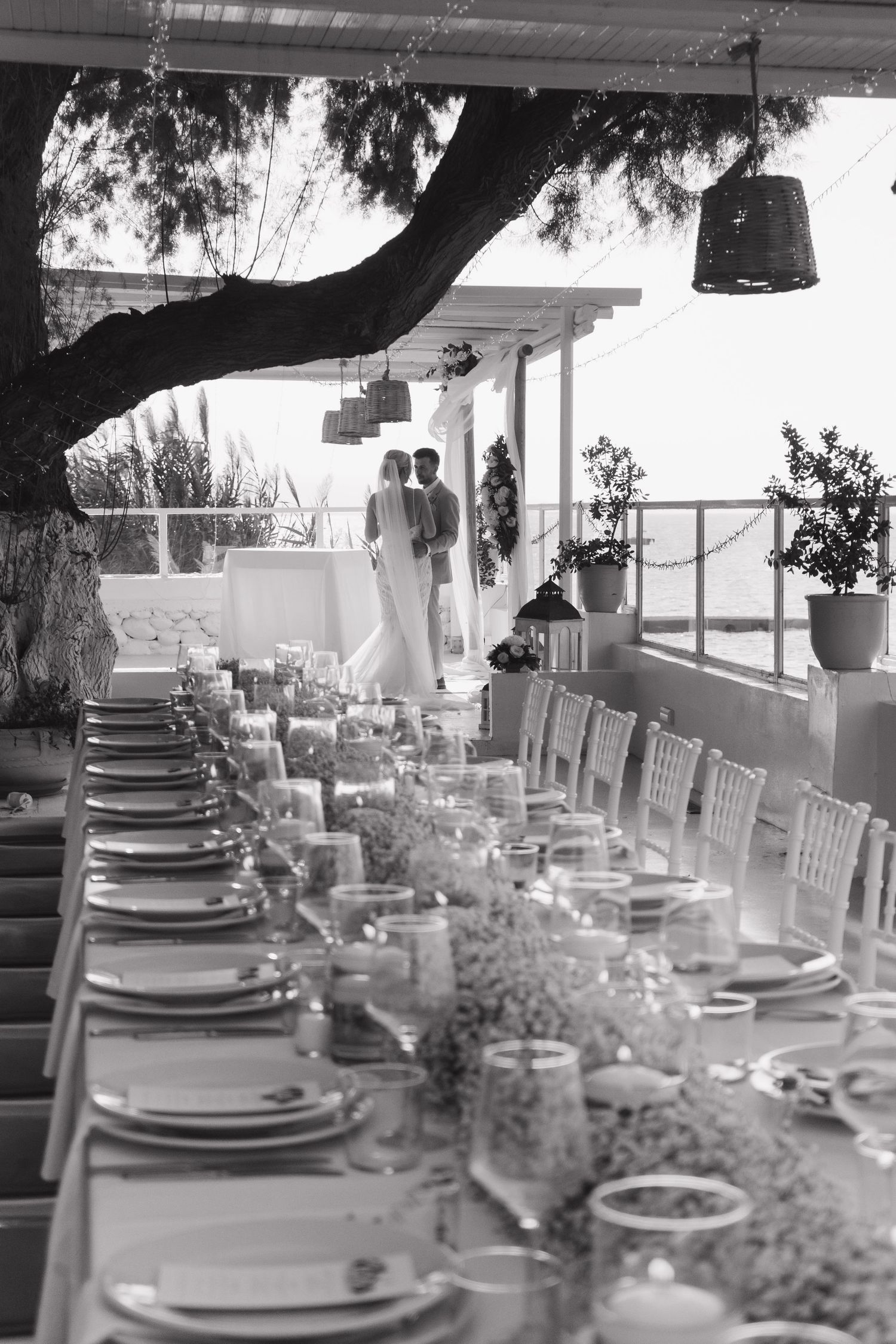 Black and white photo of an elegantly set wedding reception table with ocean view.
