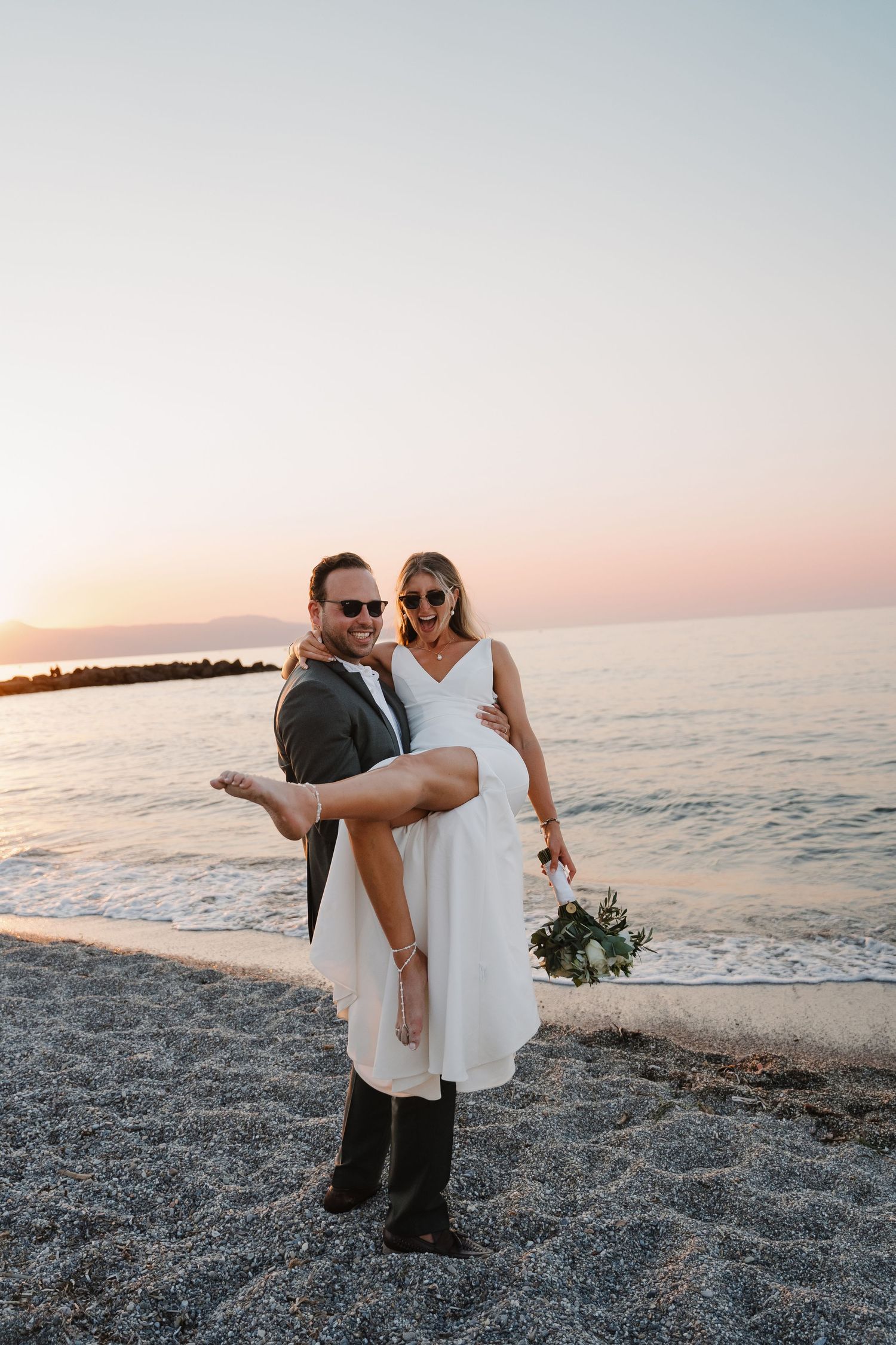 A joyful beach wedding scene with a sunset backdrop as a couple celebrates by the ocean.