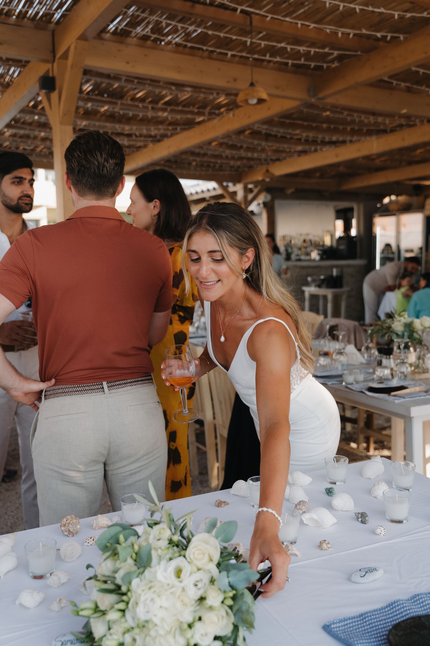 A reception scene at a beachside wedding venue with rustic wooden beams and string lights.