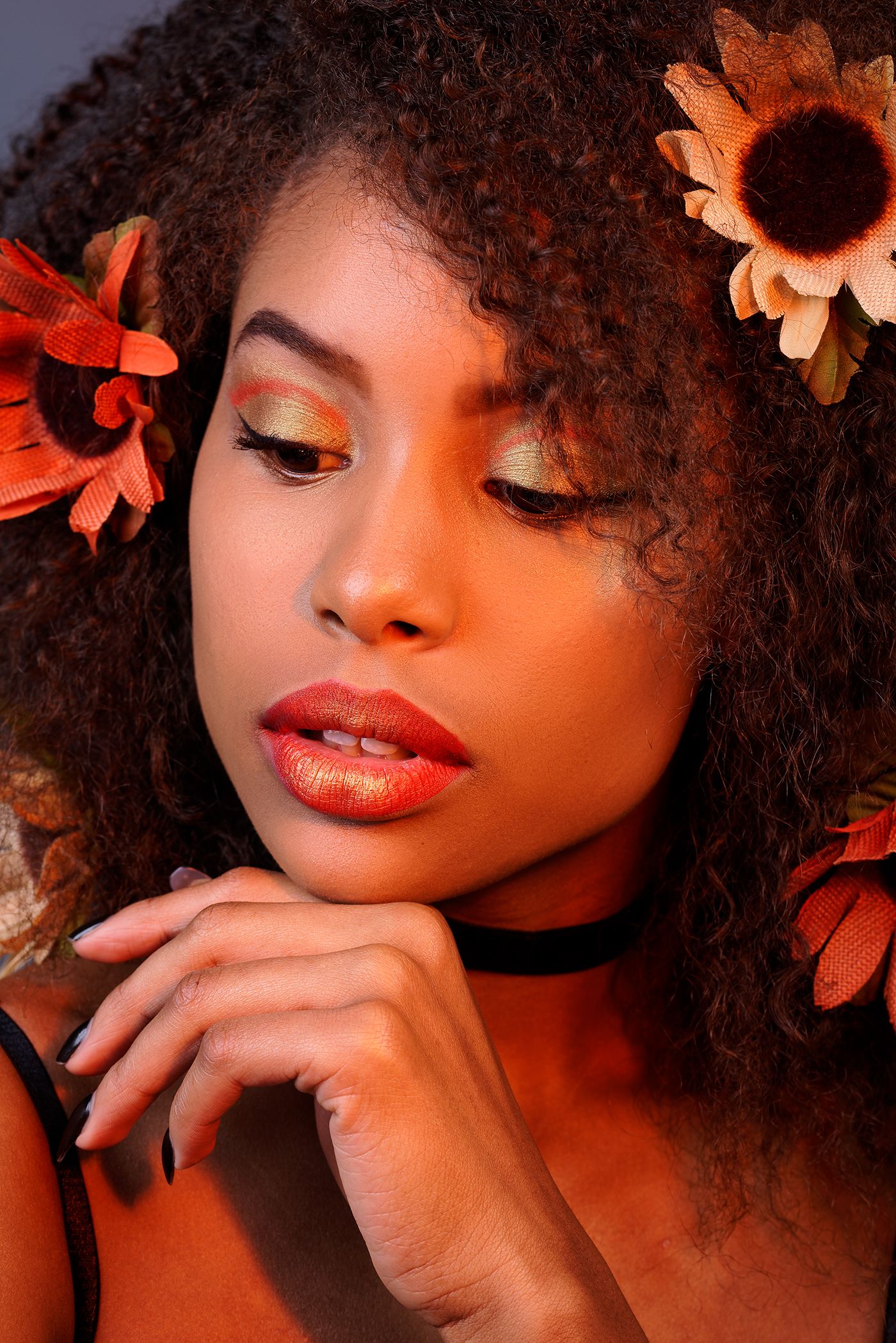 Artistic beauty luxury portrait showing vibrant red lipstick and natural curly hair with warm lighting and butterfly embellishments.