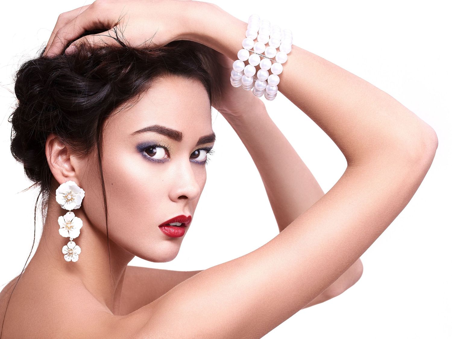 Glamour beauty portrait with pearl bracelet, floral earrings and classic red lipstick on white background.