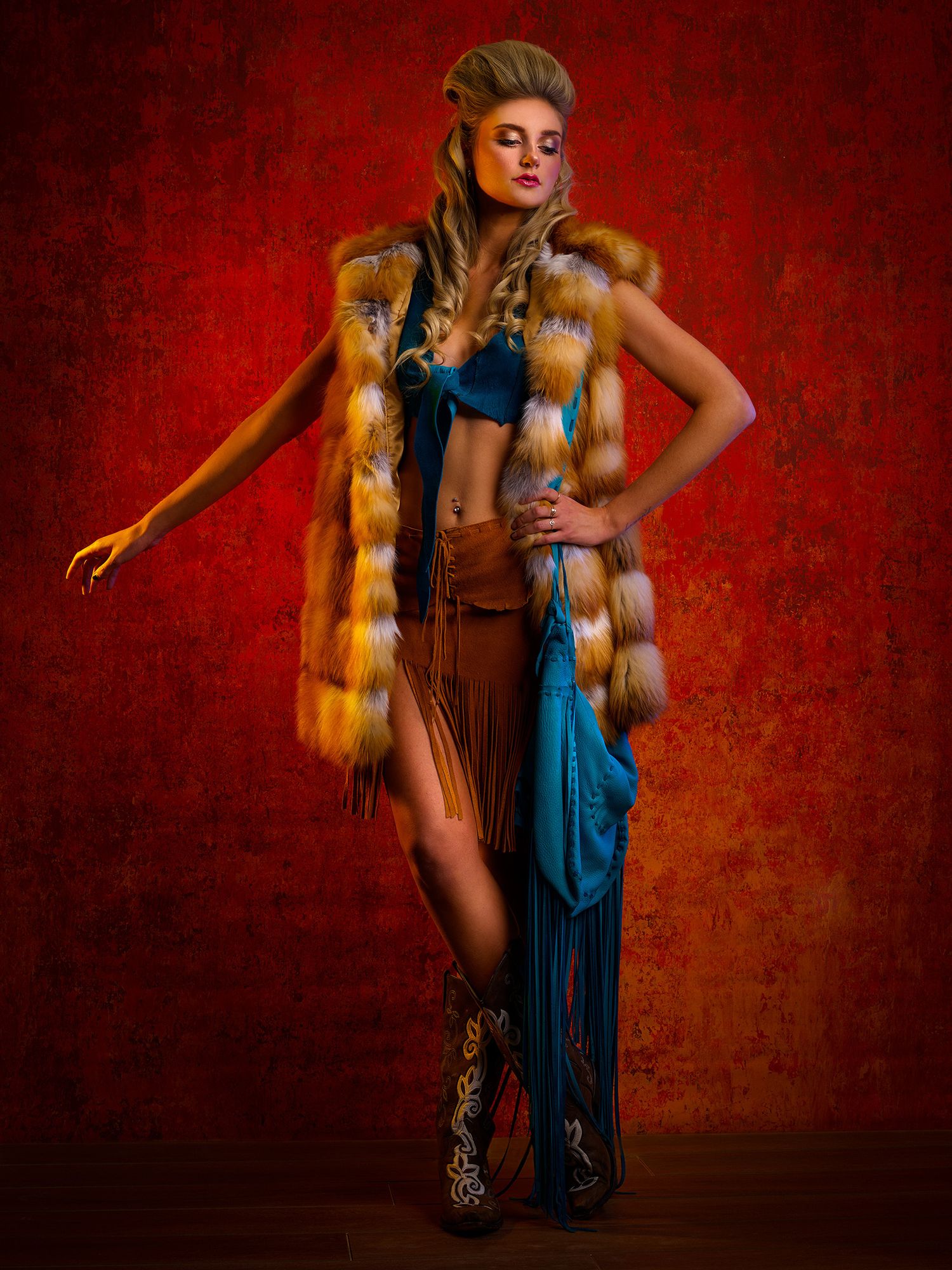 Fashion photography with brown fur vest and blue accents against a deep red textured backdrop.