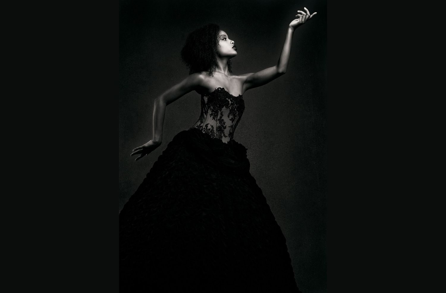 The silhouette of a person is visible in a dark, moody black and white composition with dramatic shadows.