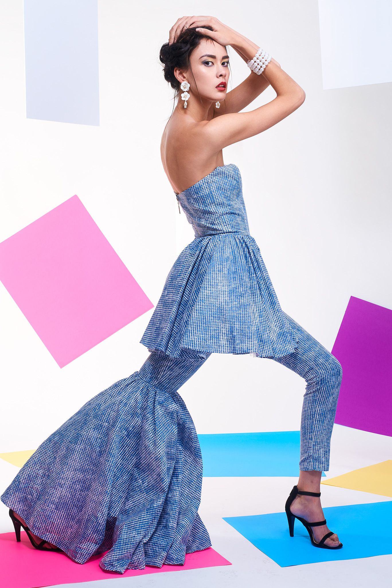 Model in flowing blue dress strikes dynamic poses against colorful paper backdrop.