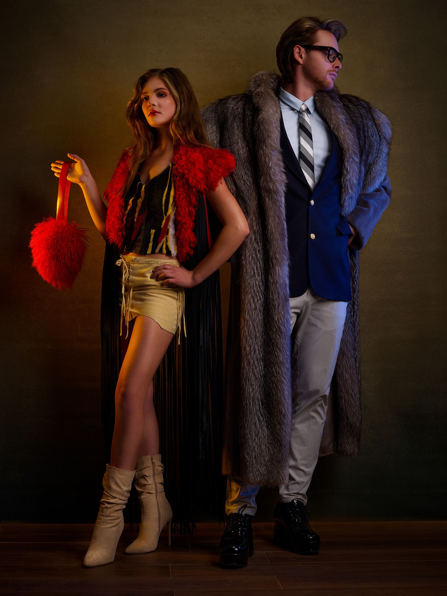 Fashion editorial scene with models in formal attire under moody red and brown lighting.