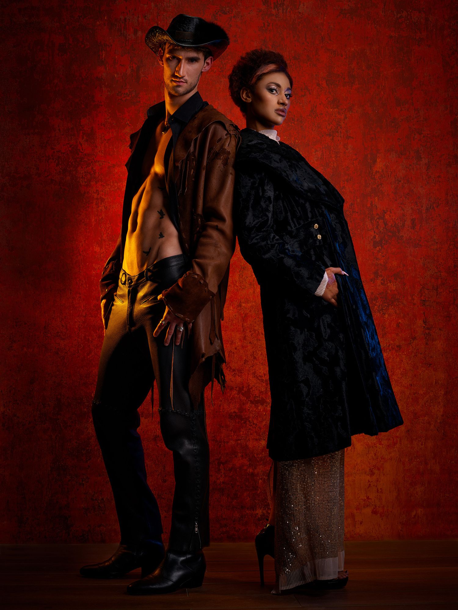 Two models in vintage-style clothing pose dramatically against a deep red background.