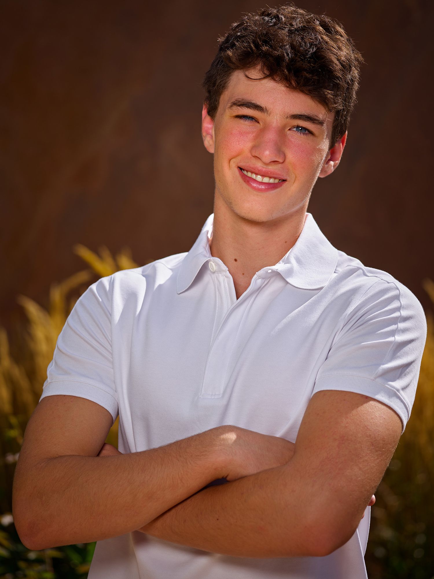 Person wearing white collared shirt poses with crossed arms against dark brown background in portrait photo series.