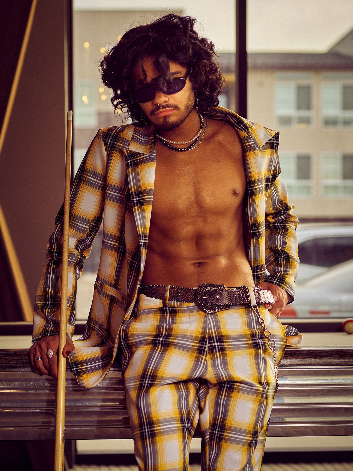 A fashion model wearing a yellow plaid outfit poses dramatically on outdoor stairs.