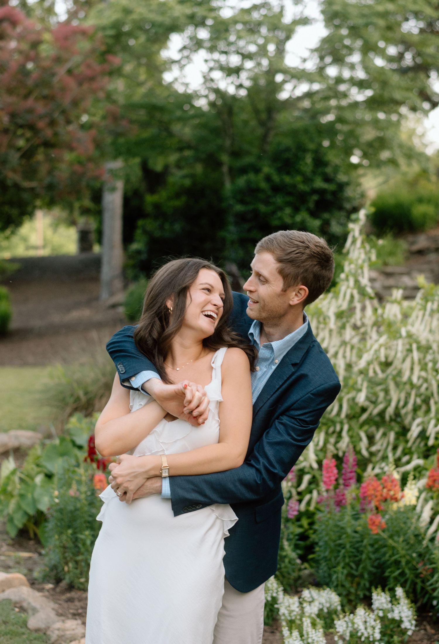 A joyful embrace in a garden setting with colorful flowers and greenery in the background.