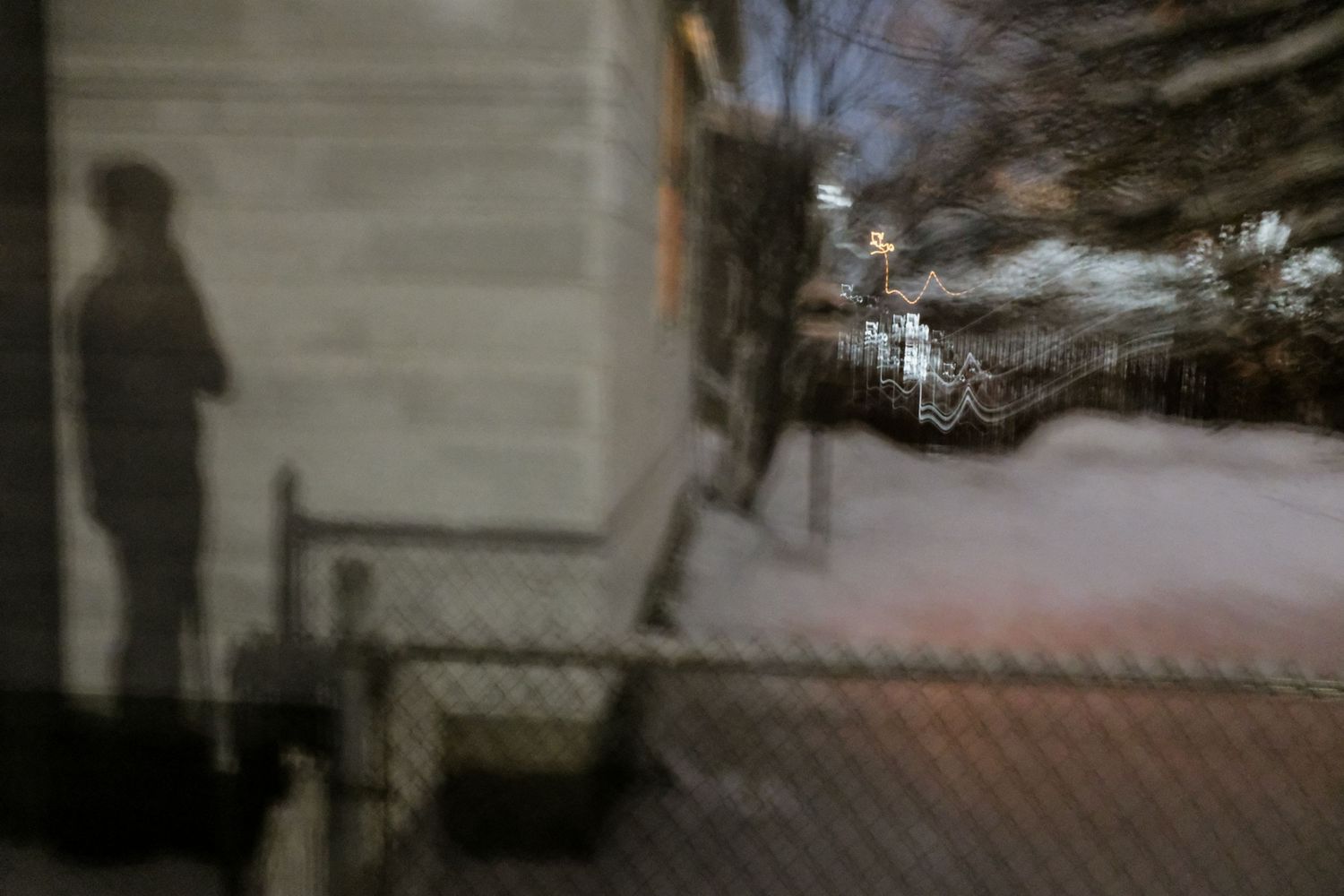 an art photo of a snowy night and a image of a person cast on a neighbor's house
