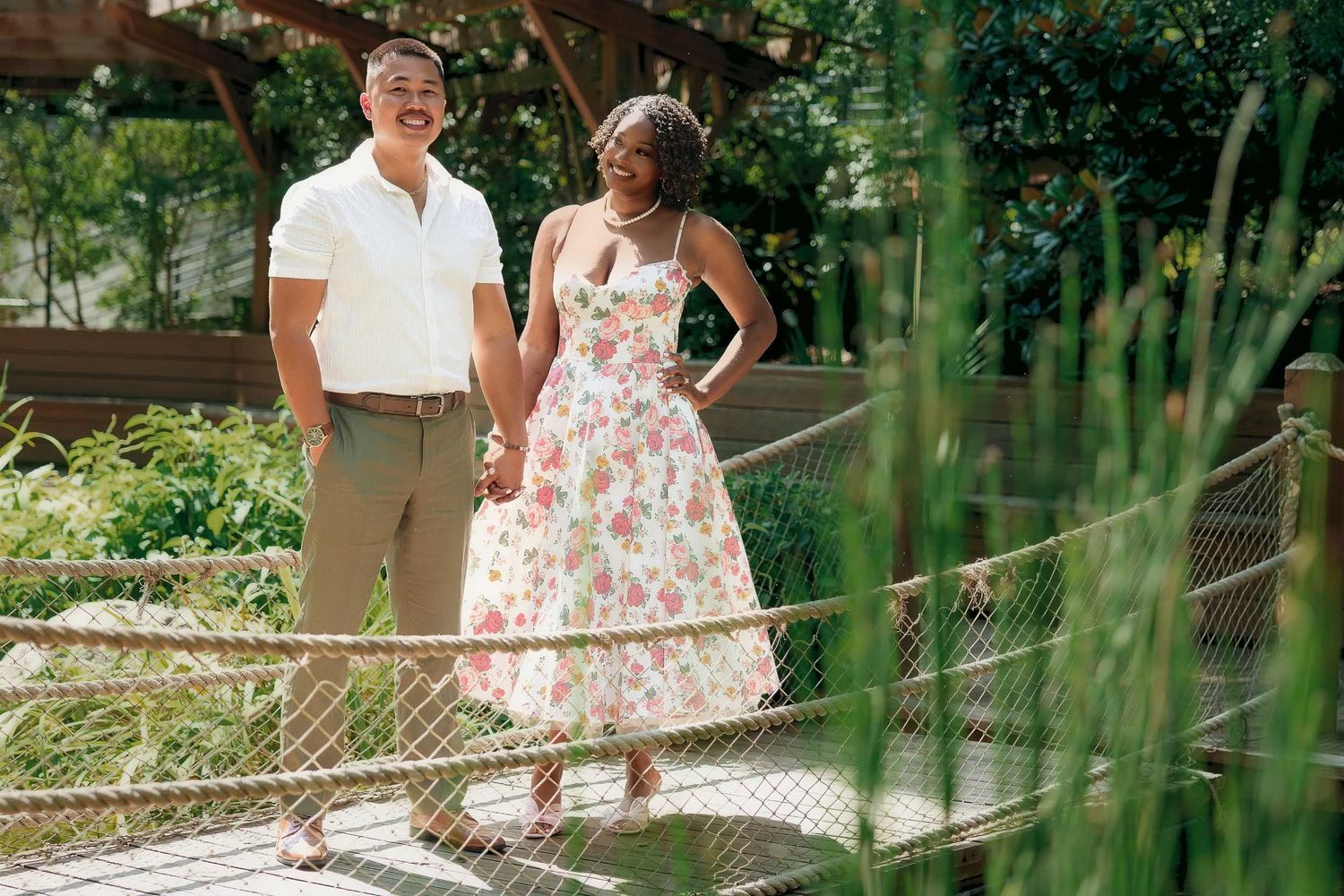 A couple standing on a garden path, with the person on the right wearing a floral dress and white heels.