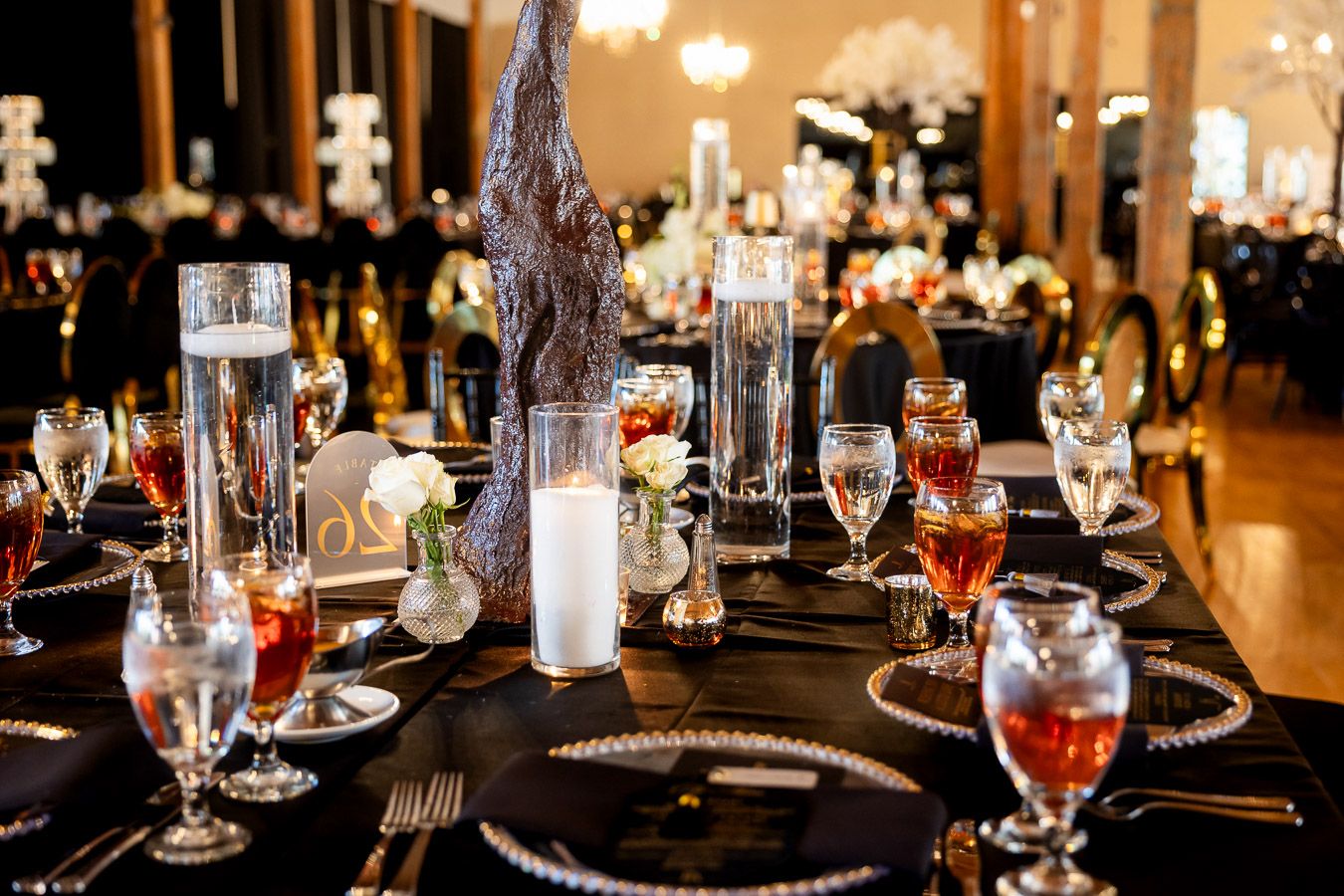 Elegant wedding reception table with black linens, crystal glassware and lit candles creating romantic ambiance.