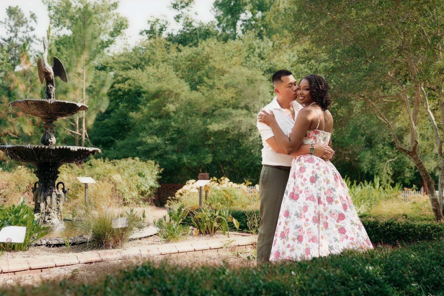 Flower garden photoshoot in a dreamy park setting with white floral summer dress and lush greenery in natural light.