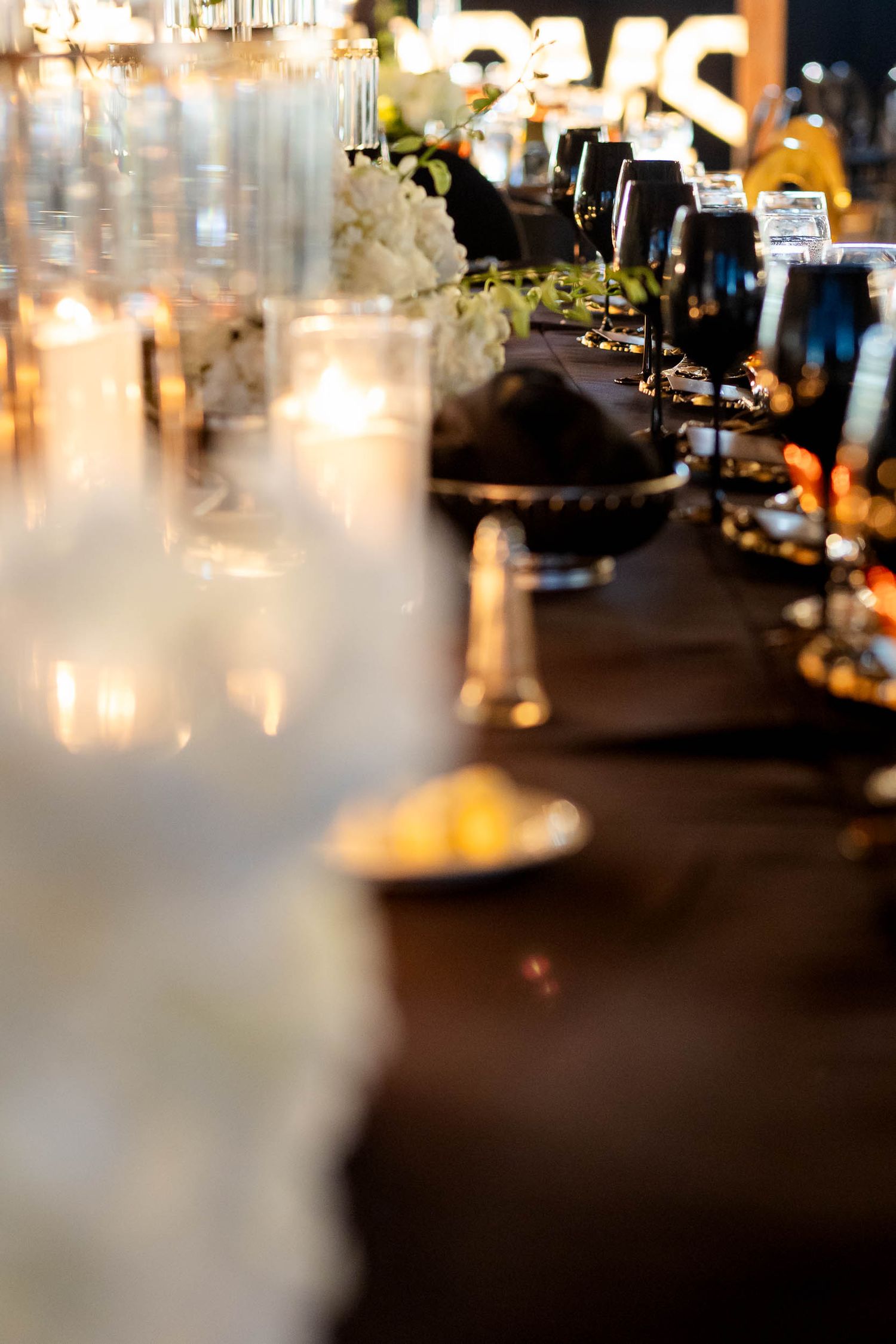 Soft focus candlelit table setting with wine glasses and elegant decorations in a restaurant's warm ambiance.
