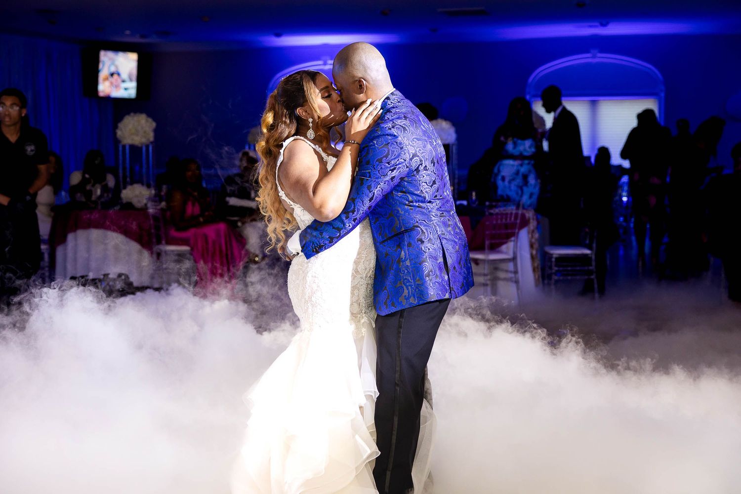 A romantic first dance moment in a misty atmosphere with fog effects and blue lighting at an elegant wedding reception.
