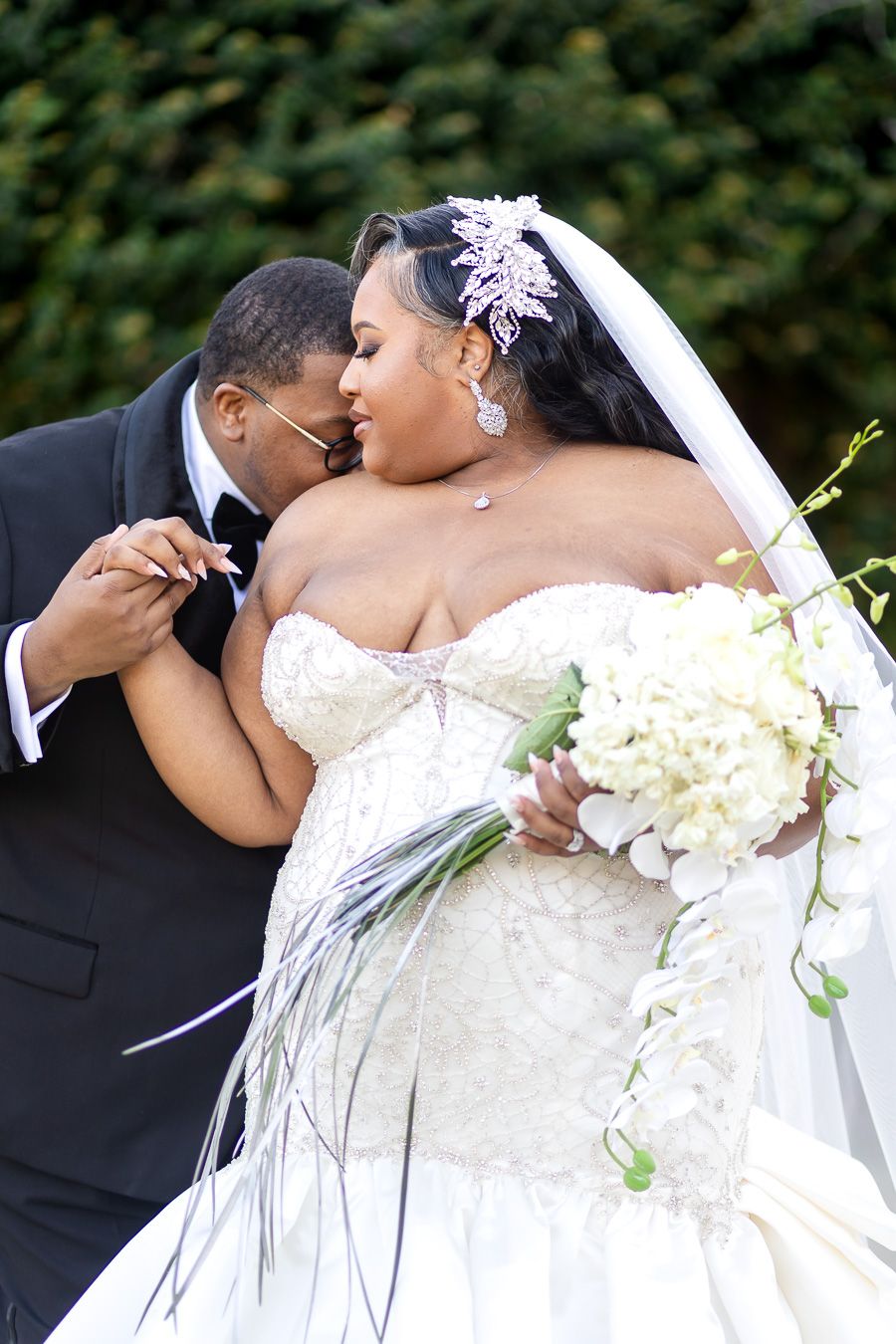 A tender moment between newlyweds in a romantic garden setting with a beautiful white bridal bouquet.