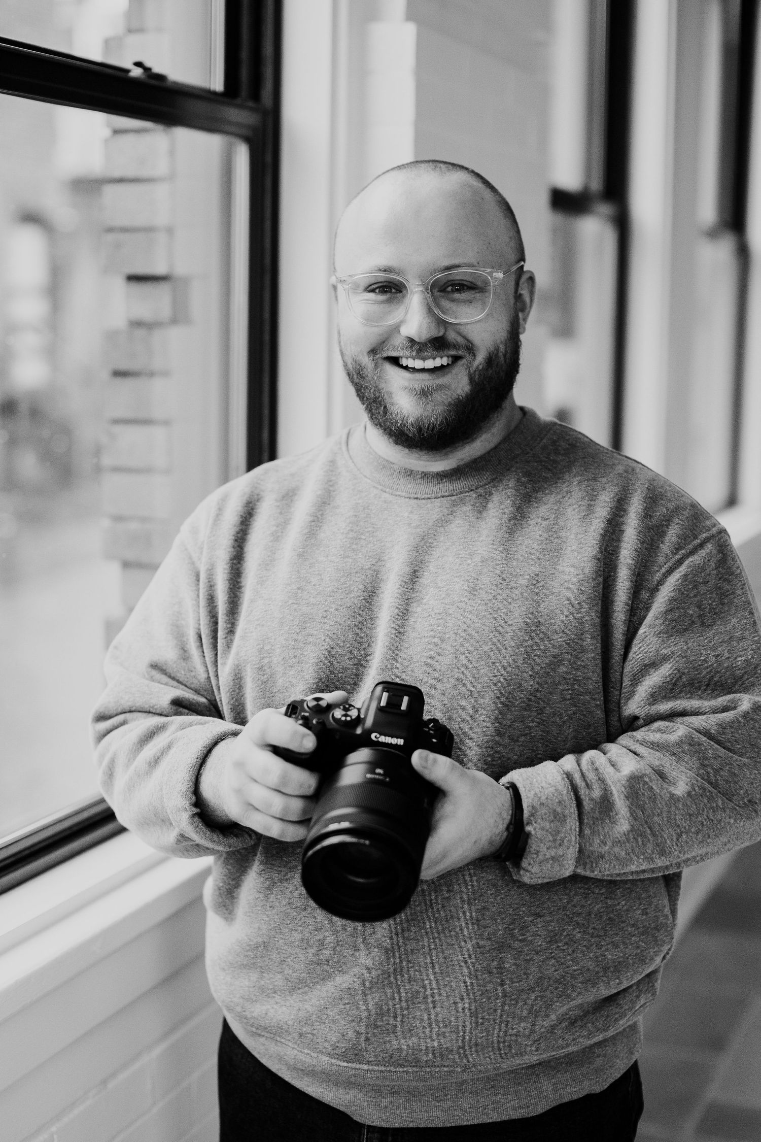 Person in gray sweater demonstrating different camera positions and angles near a window.