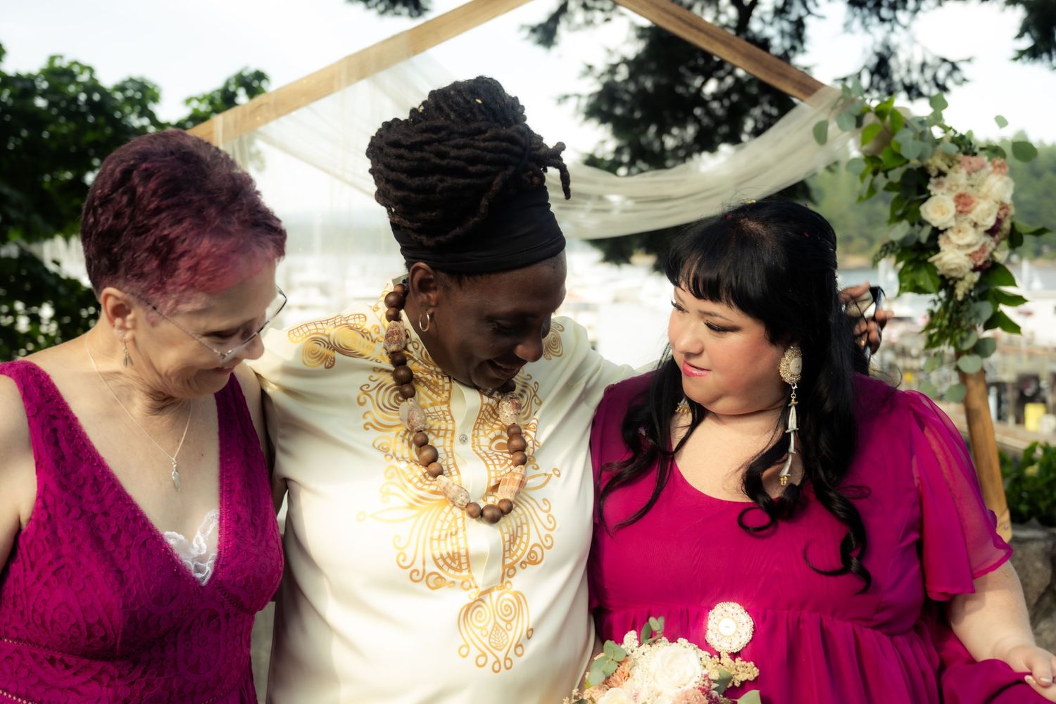 Three people share an intimate moment at an outdoor wedding celebration.