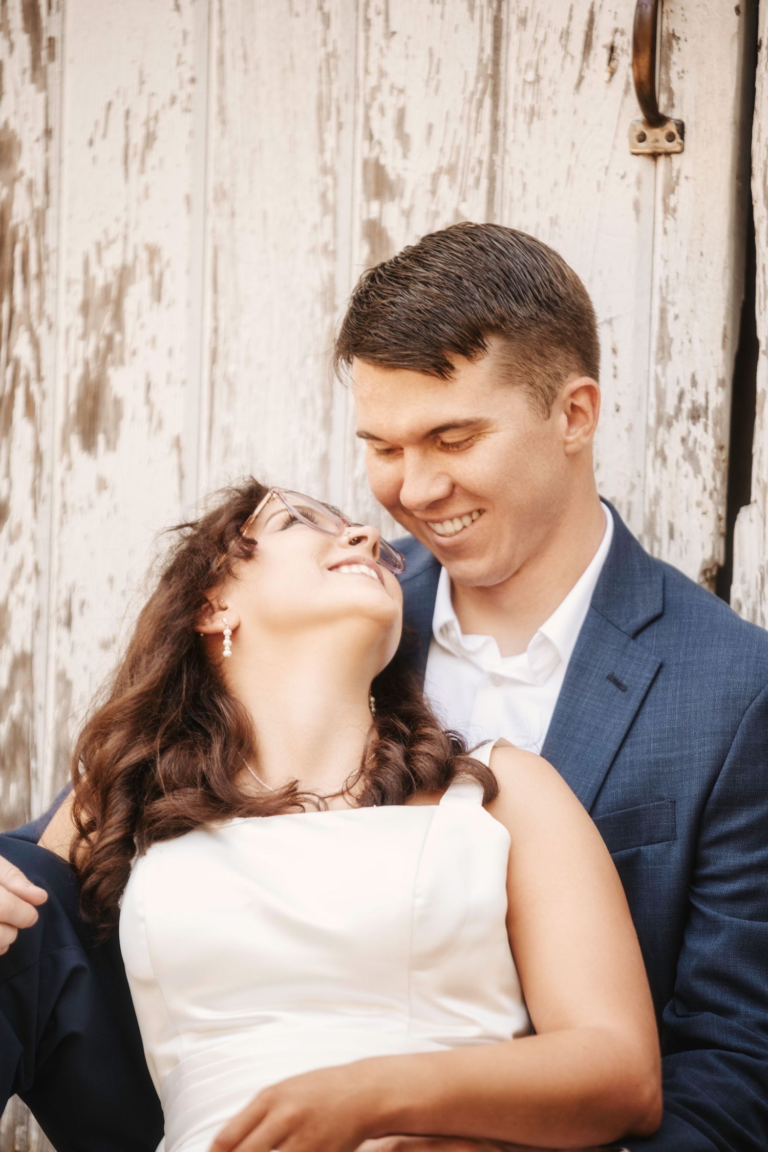 A tender moment captured between a couple against a weathered wooden backdrop.