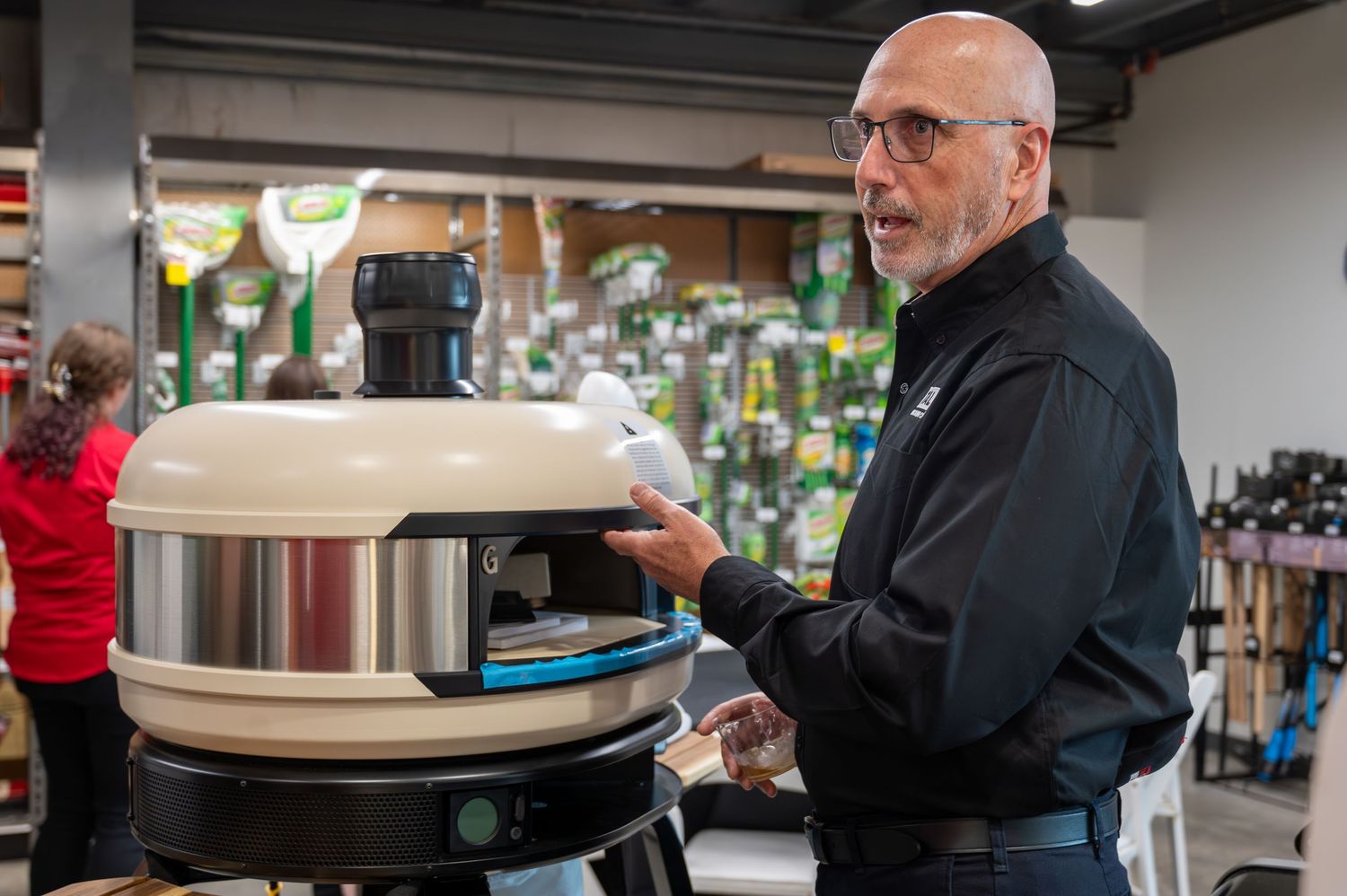 Store employee demonstrating kitchen appliance during retail presentation.