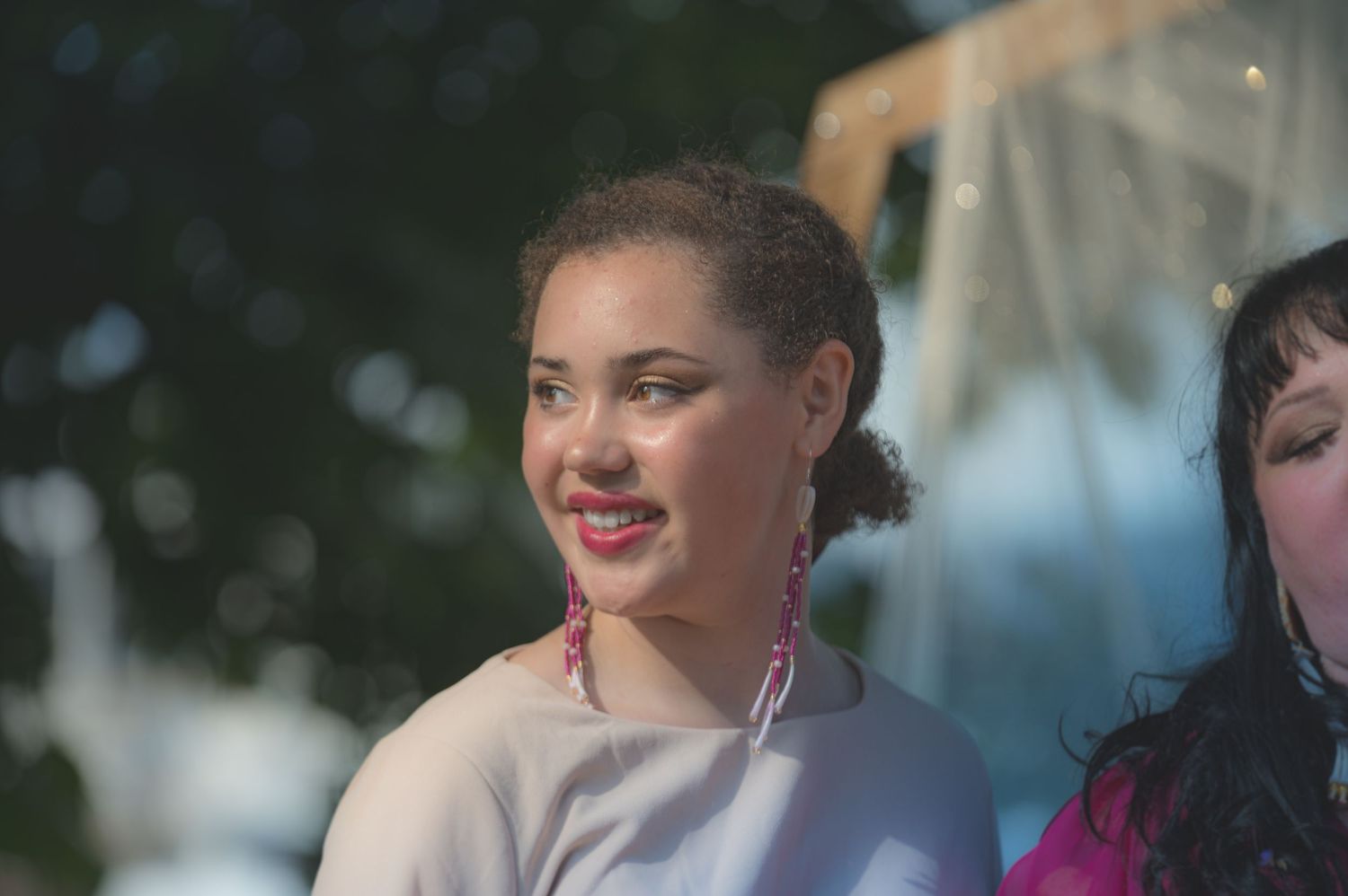 Wedding guest smiles brightly during an outdoor celebration.