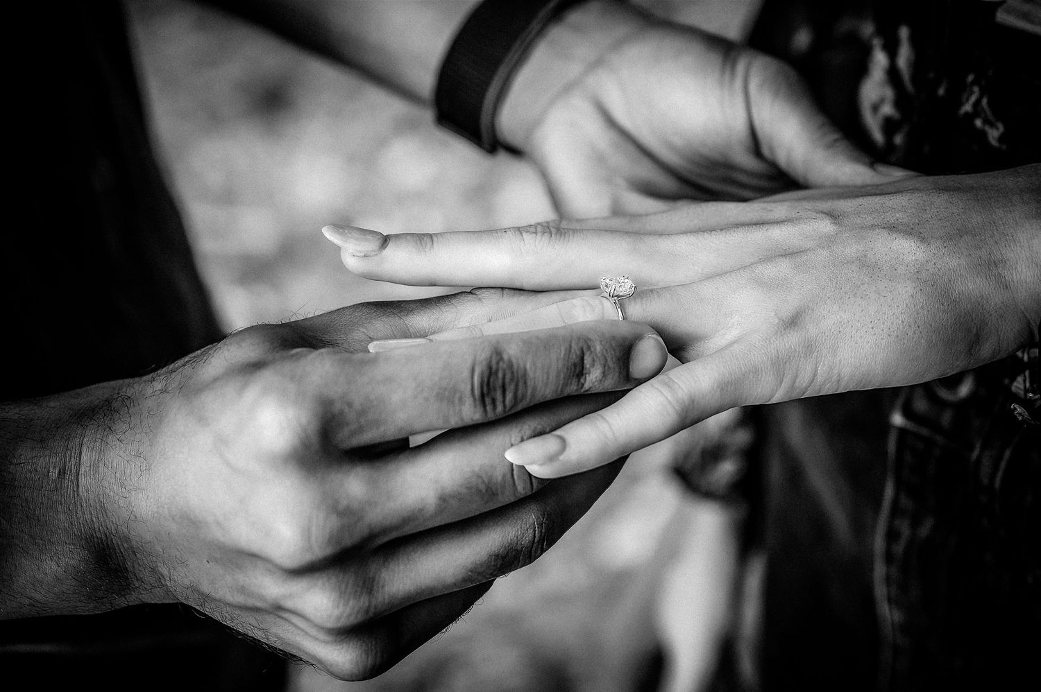 Black and white close-up of hands exchanging rings during an intimate moment.