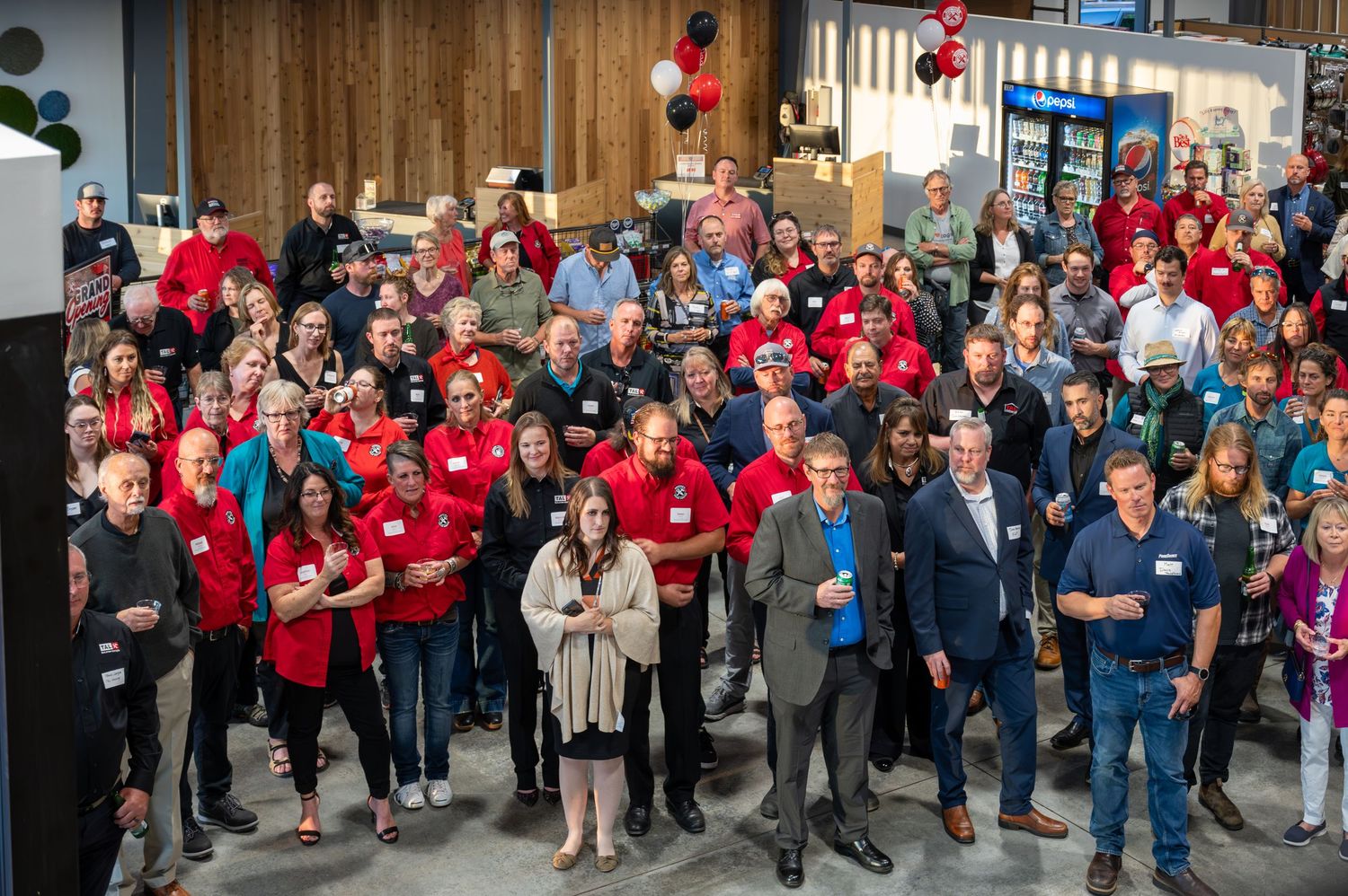 Large crowd of people wearing red and blue shirts gathered at indoor event space.
