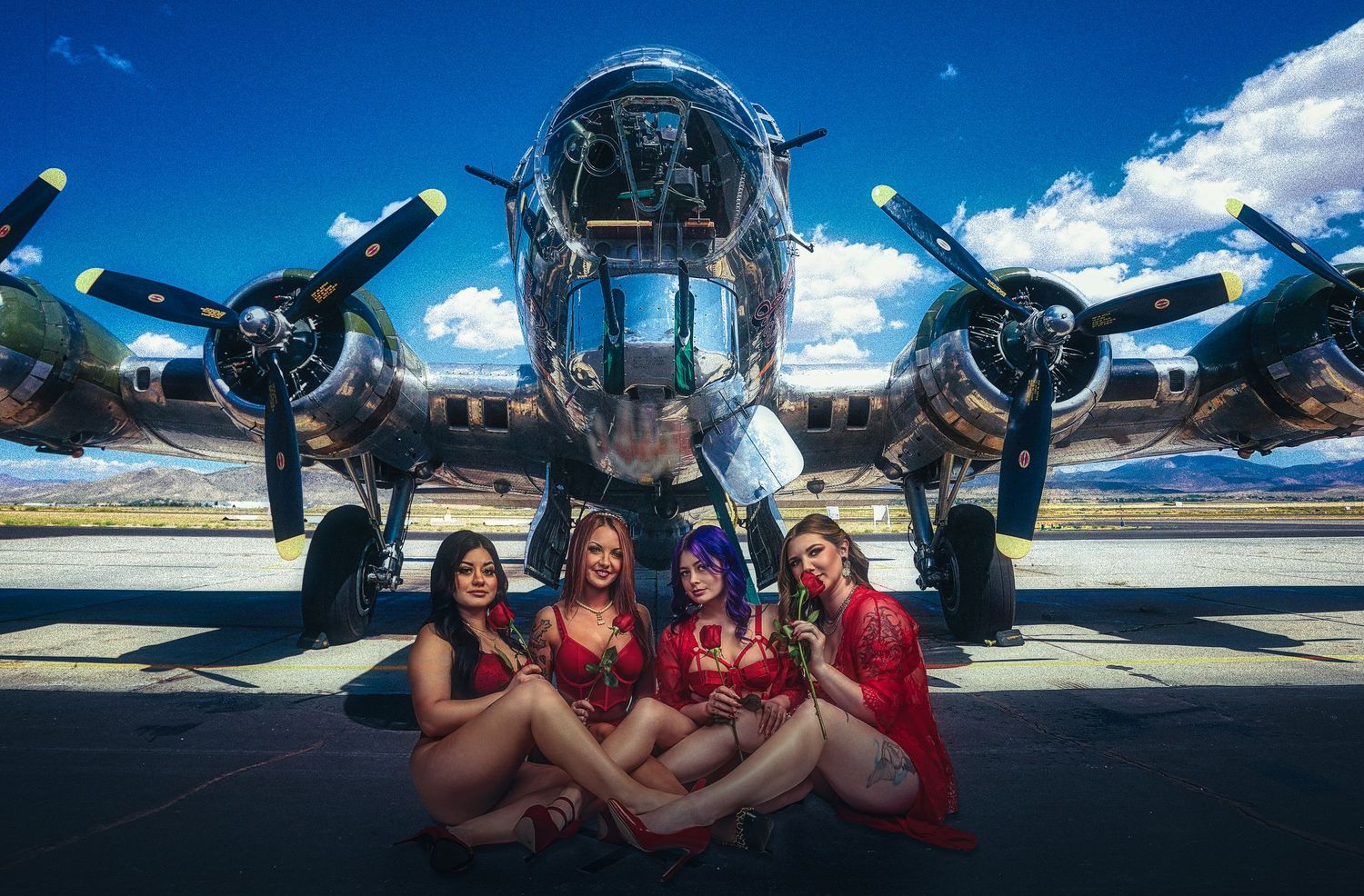 Group photo in red outfits posed in front of classic WWII bomber aircraft.