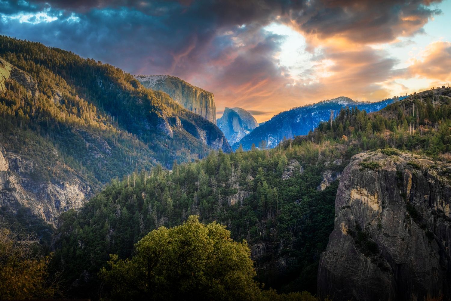 Dramatic sunset over Yosemite Valley with granite cliffs and forested slopes.
