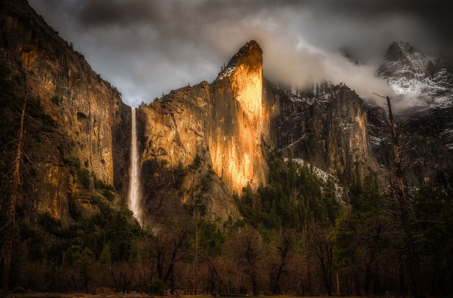 Dramatic view of Bridalveil Fall cascading down illuminated cliff face in Yosemite Valley.