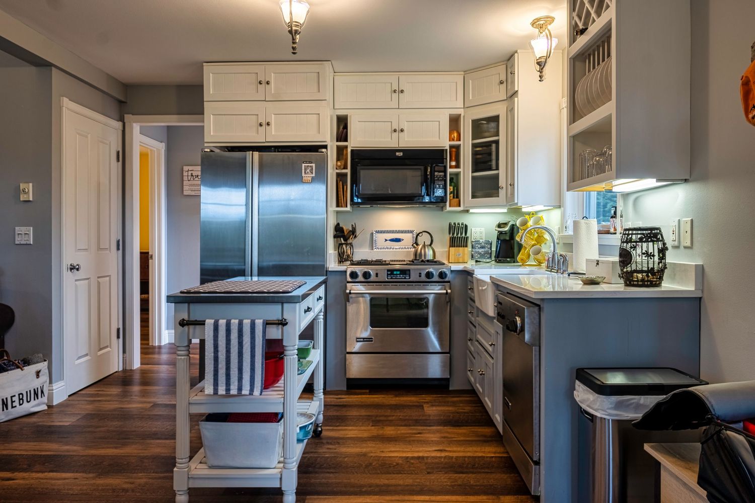 Modern gray kitchen with stainless steel appliances, hardwood floors and white cabinets.