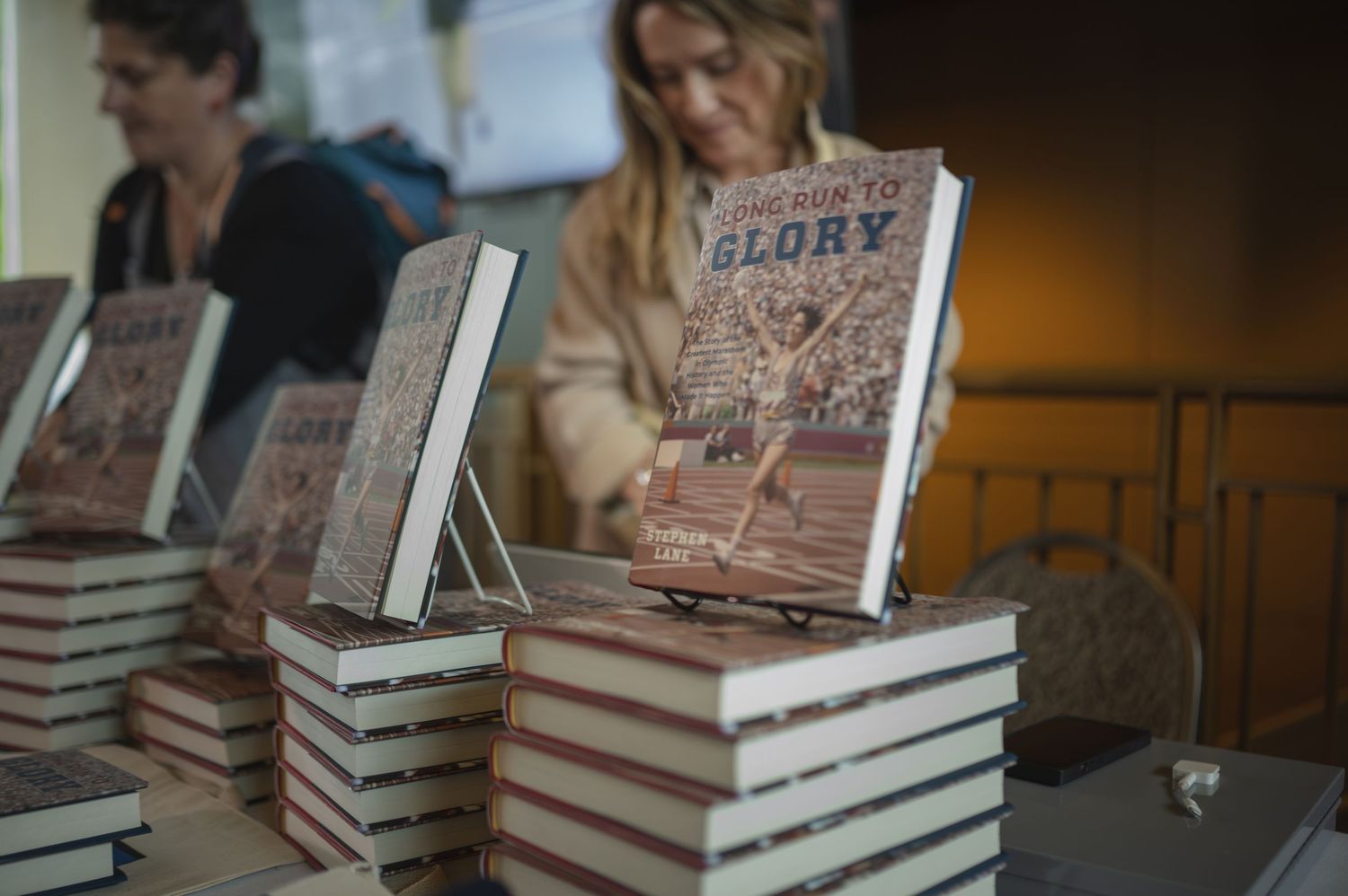 Stack of books displayed on table at book signing or promotional event.