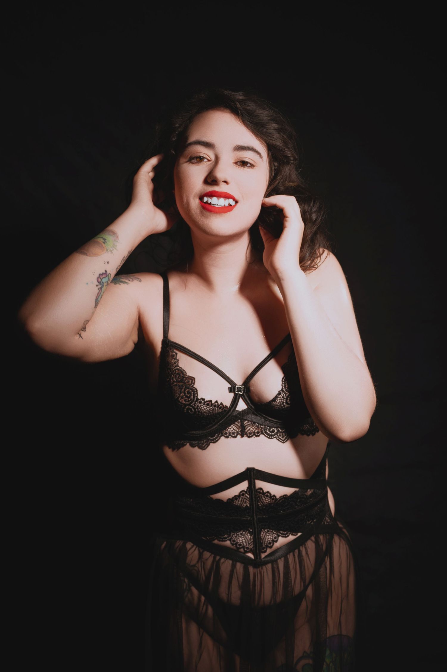 Glamour portrait against black background with dramatic lighting and lace details.