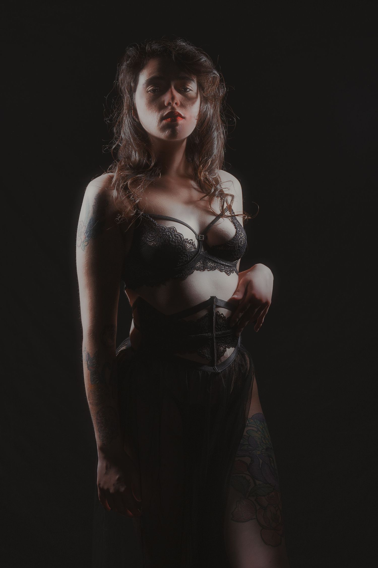 Dark and moody boudoir portrait with dramatic shadows and vintage styling.
