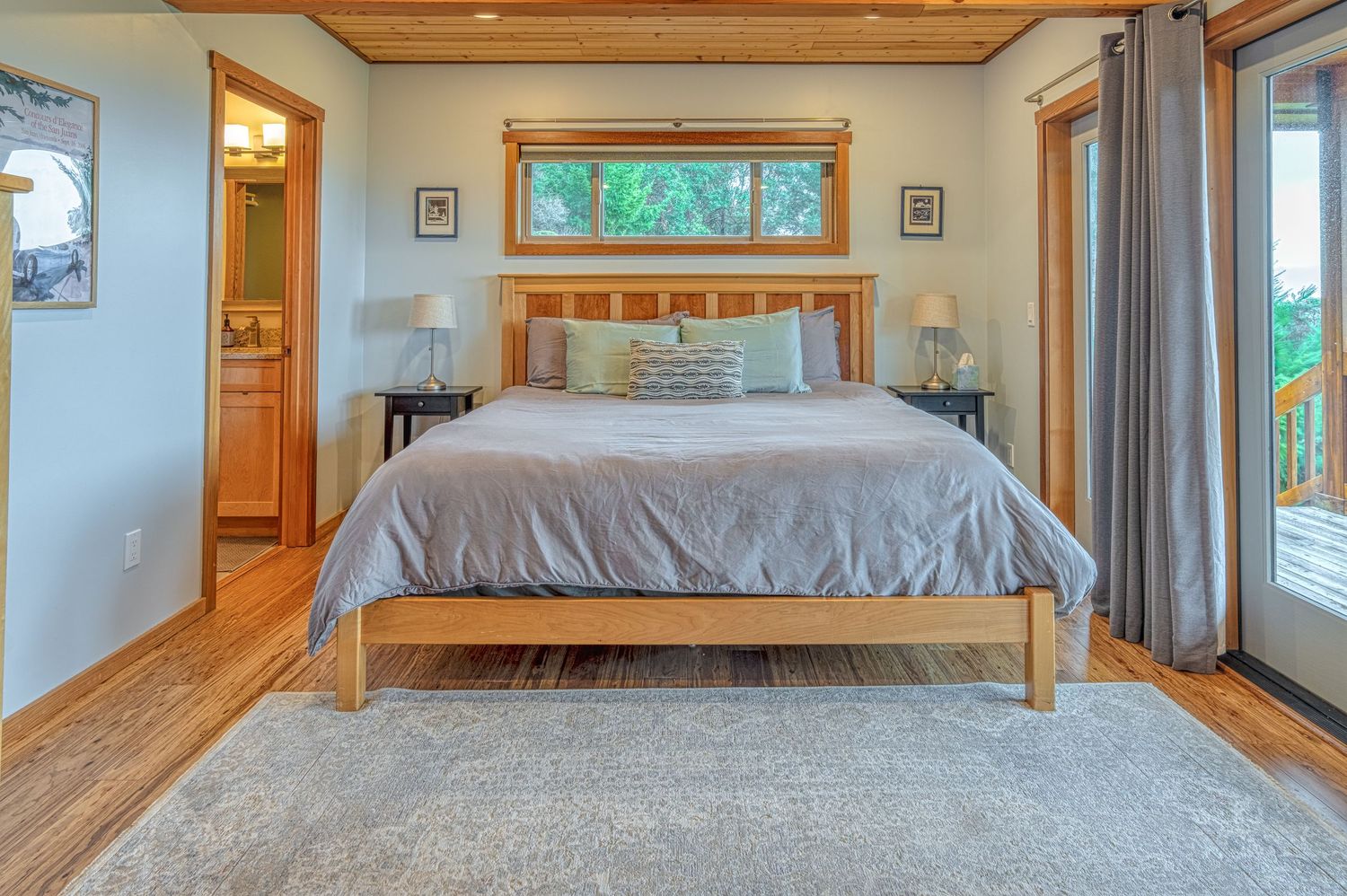 Serene bedroom with wooden floors, king bed, and sliding glass doors leading to outdoor deck.
