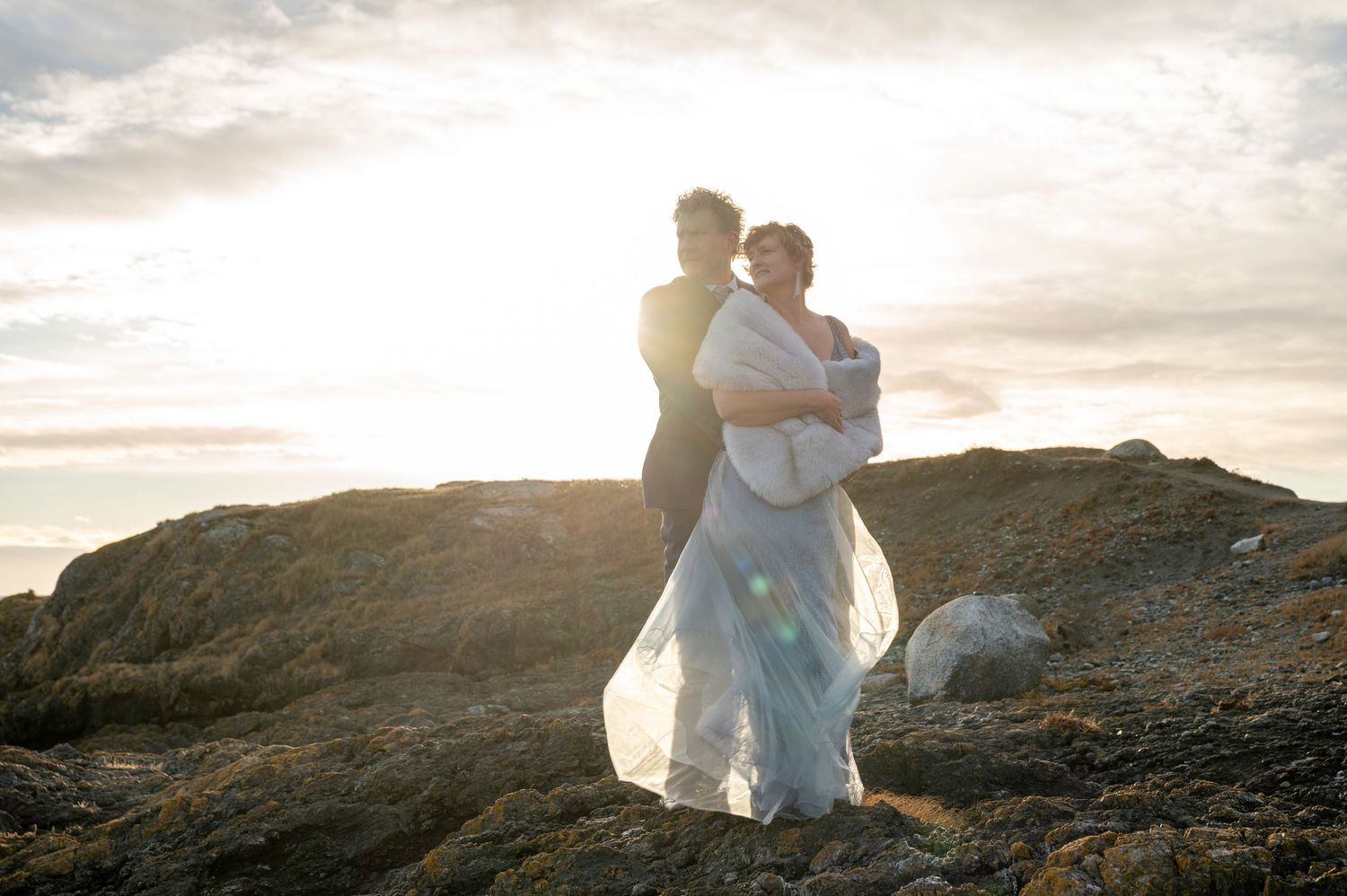 A romantic sunset moment on coastal rocks with flowing fabric catching the golden light.
