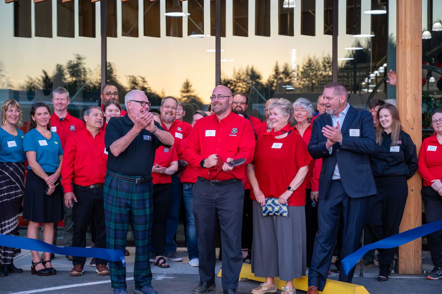 Group of attendees in red and blue uniforms gathered outdoors at sunset event.