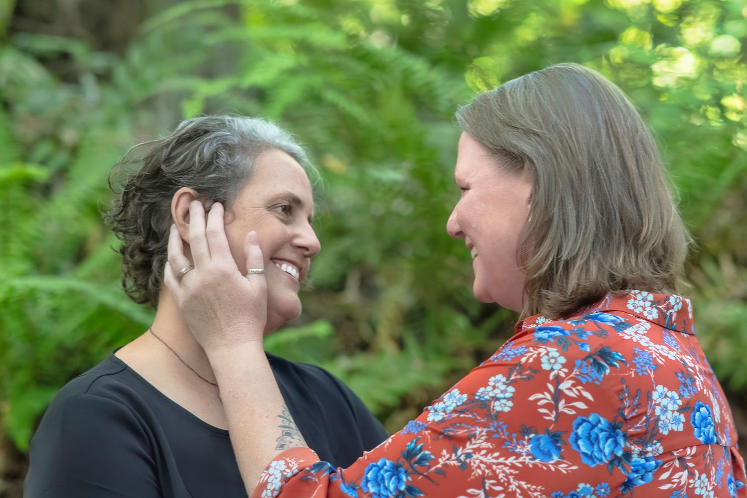 Two people sharing an intimate tender moment outdoors surrounded by greenery.