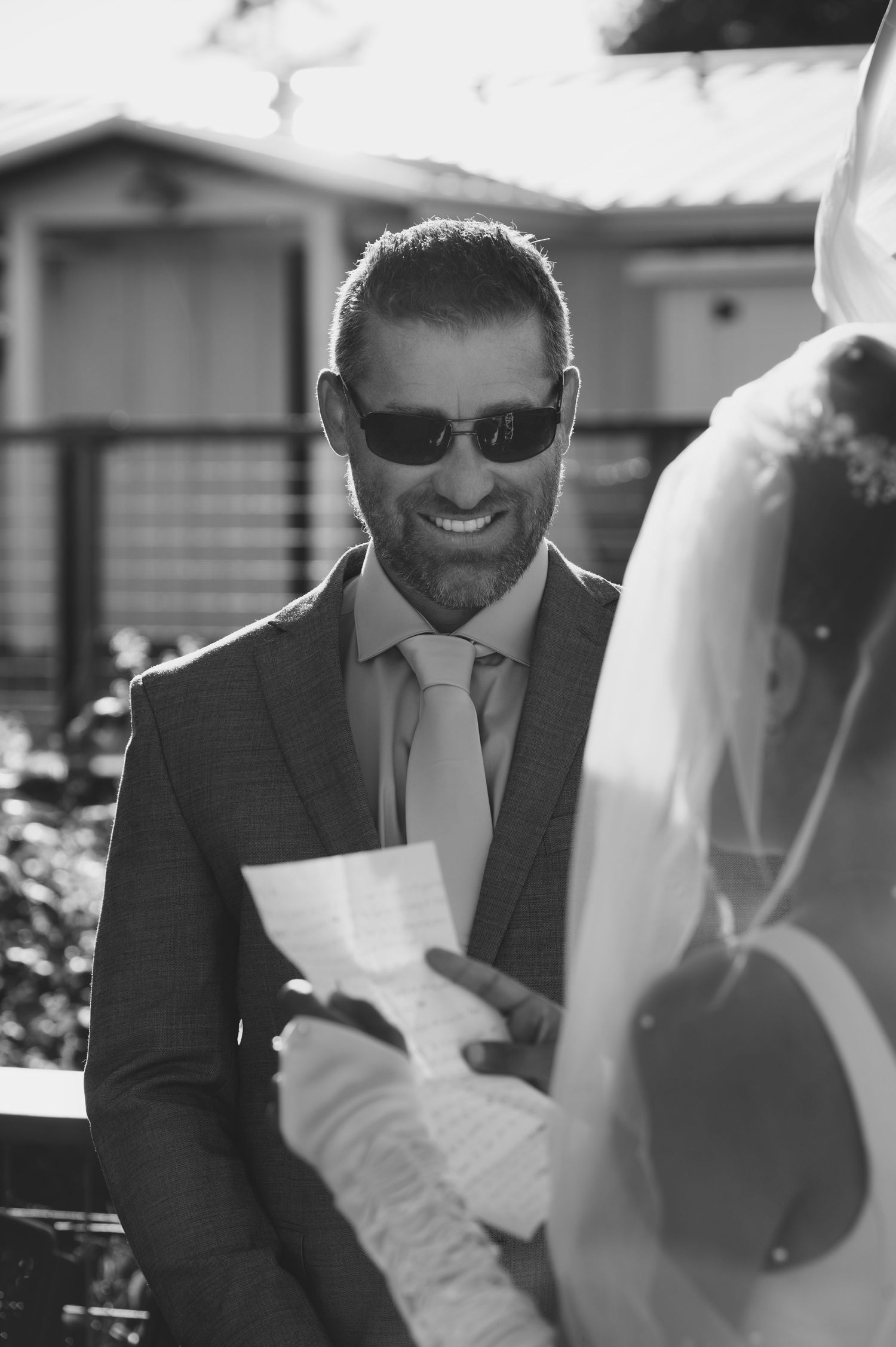 Wedding moment with someone in sunglasses reading vows during an outdoor ceremony.