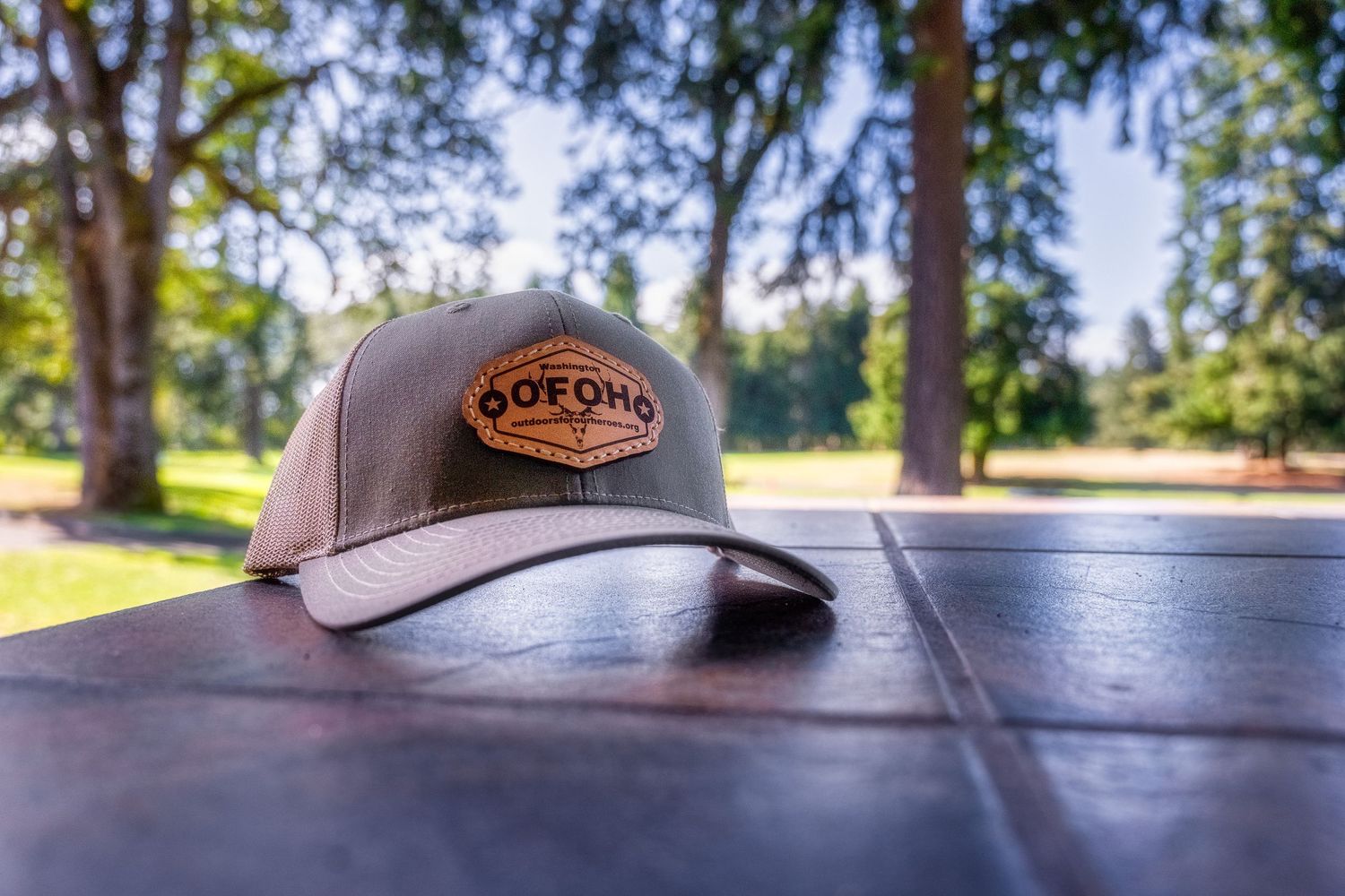 Brown trucker hat with Gordo's logo sitting on wooden table in outdoor setting.