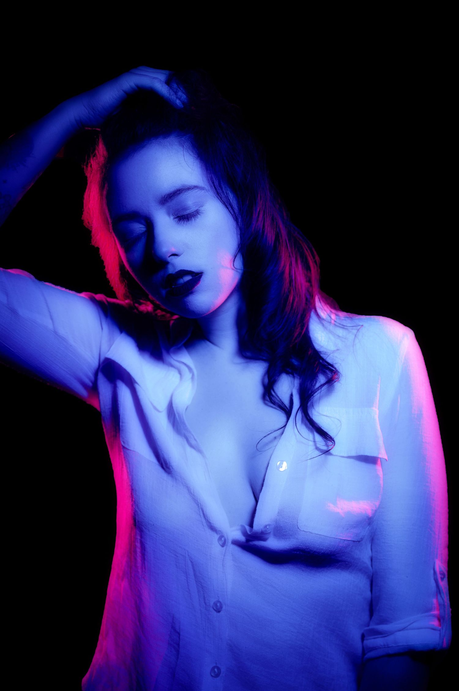 Artistic portrait with dramatic blue and red lighting effects creating a moody atmosphere.
