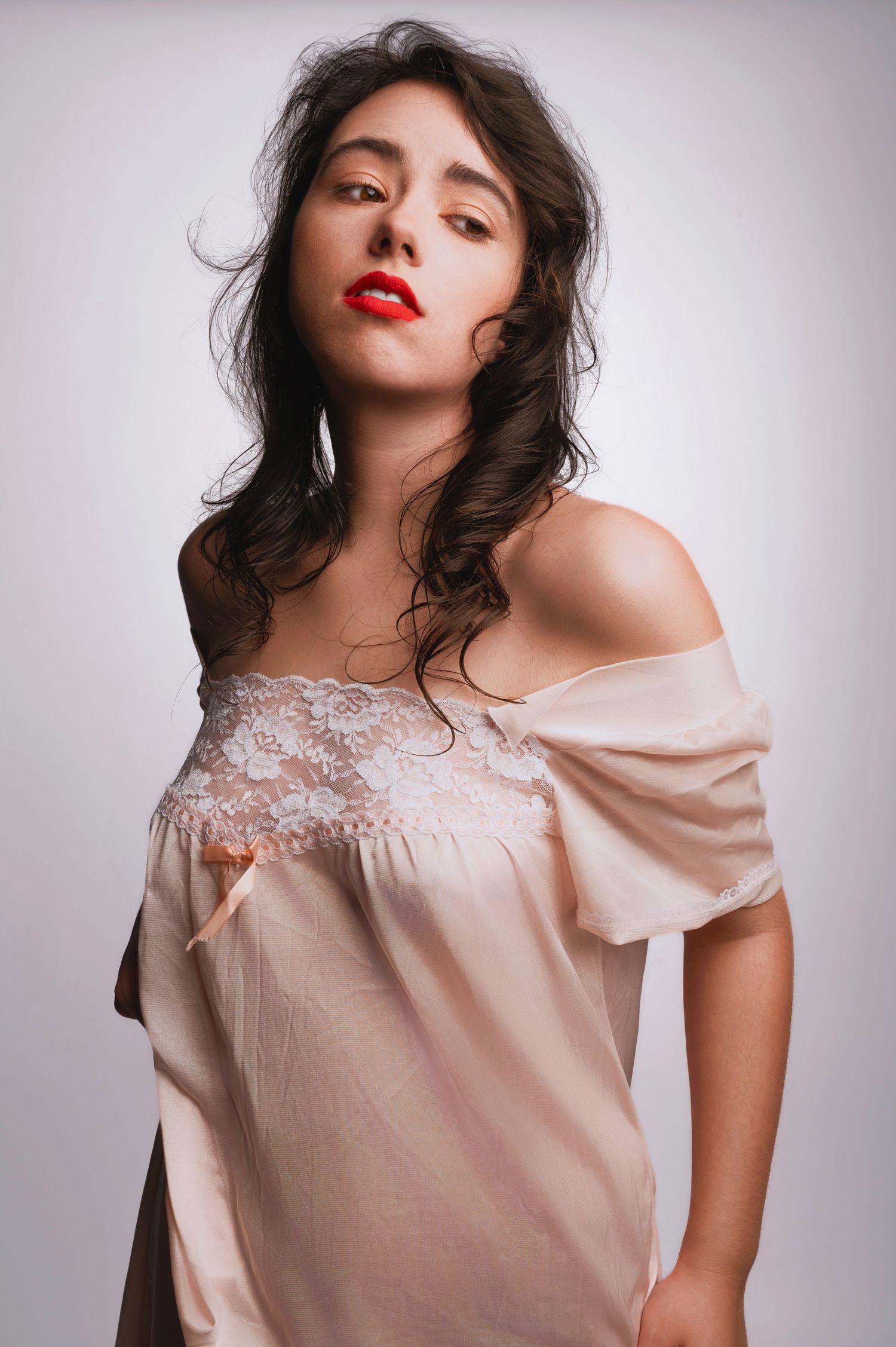 Off-shoulder cream lace dress portrait with vintage styling and red lipstick.