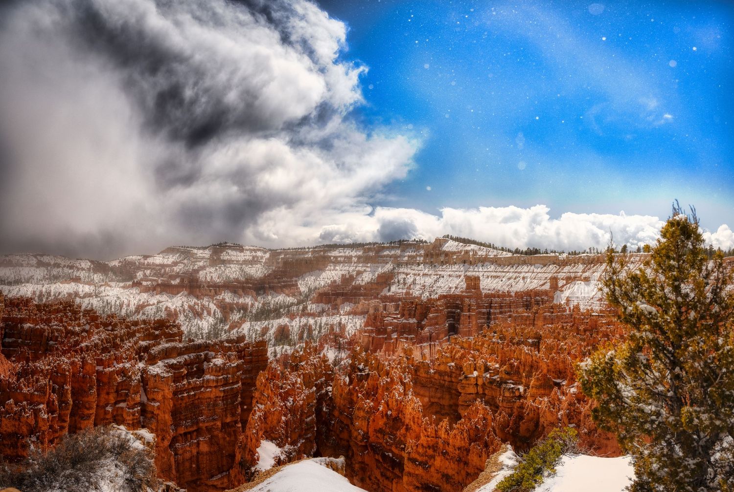 Snow-dusted red rock formations at Bryce Canyon with dramatic storm clouds overhead.