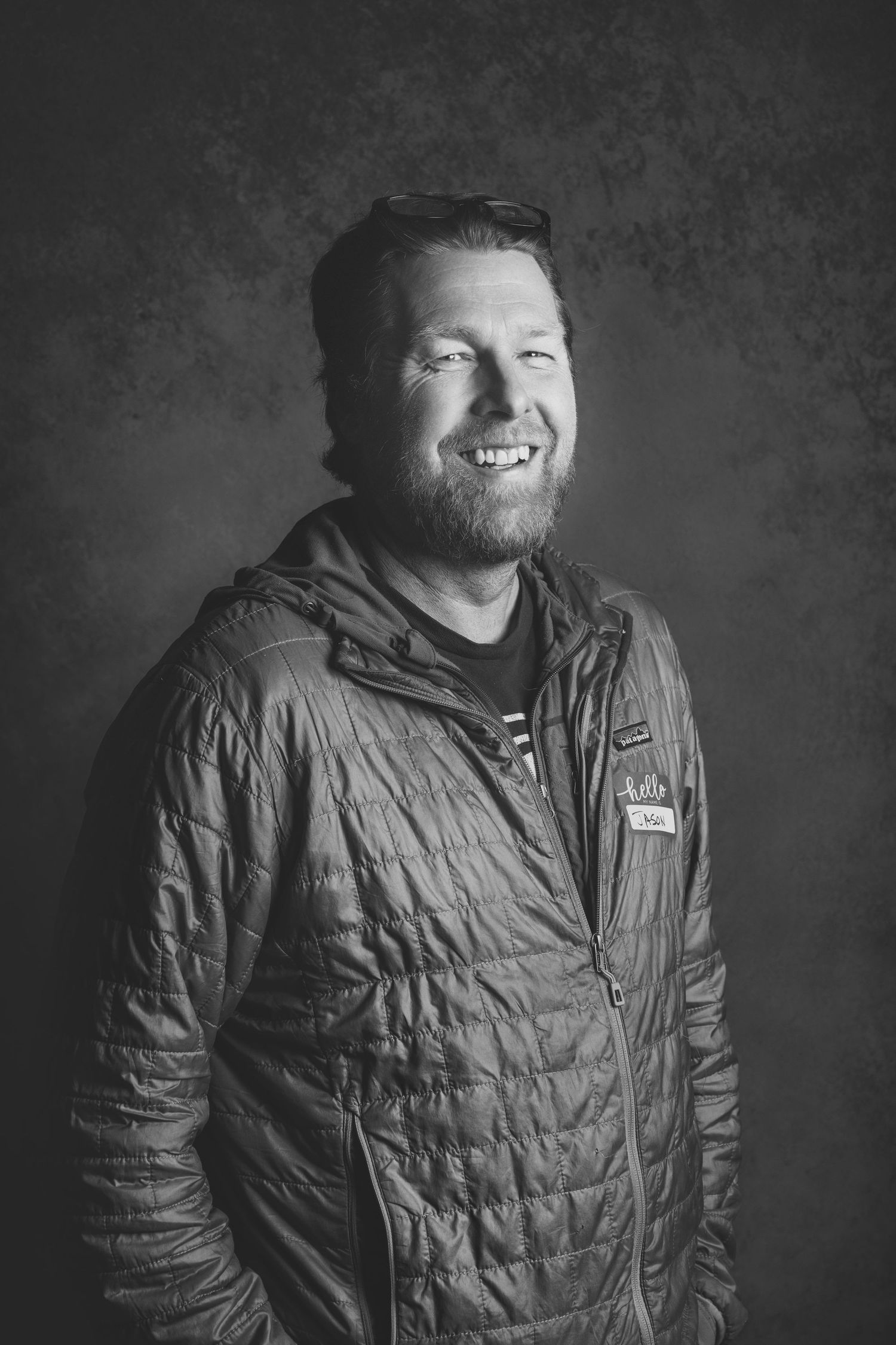 Black and white portrait of person in quilted jacket smiling.