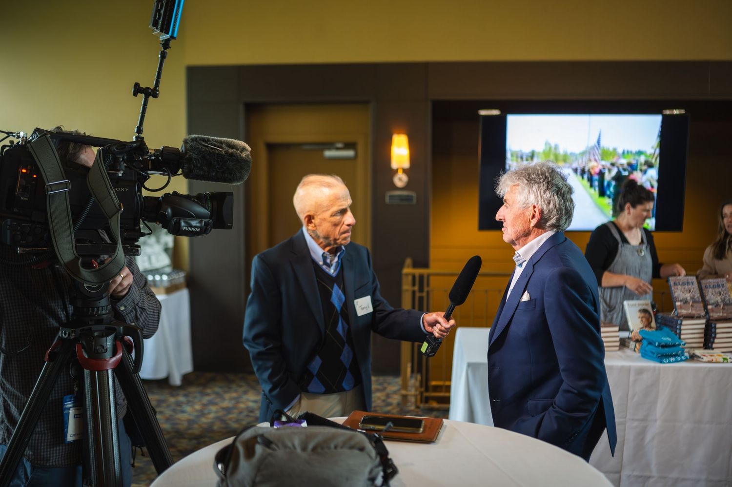 Two professionals having a discussion near a camera setup at a business event.