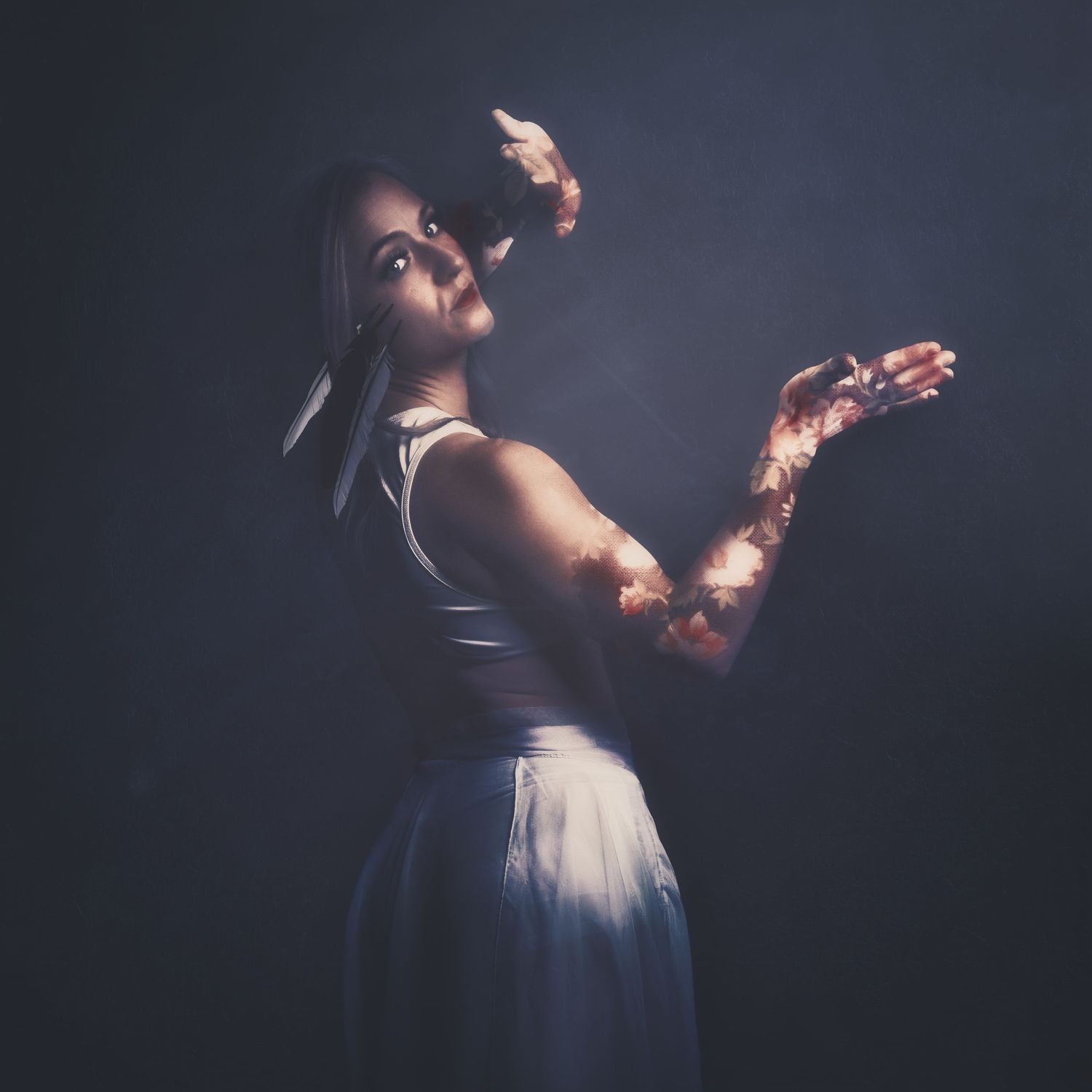Dramatic figure in white dress with glowing arms poses against dark background.
