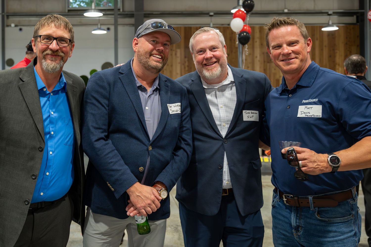 Business professionals networking at corporate event with company branding visible.